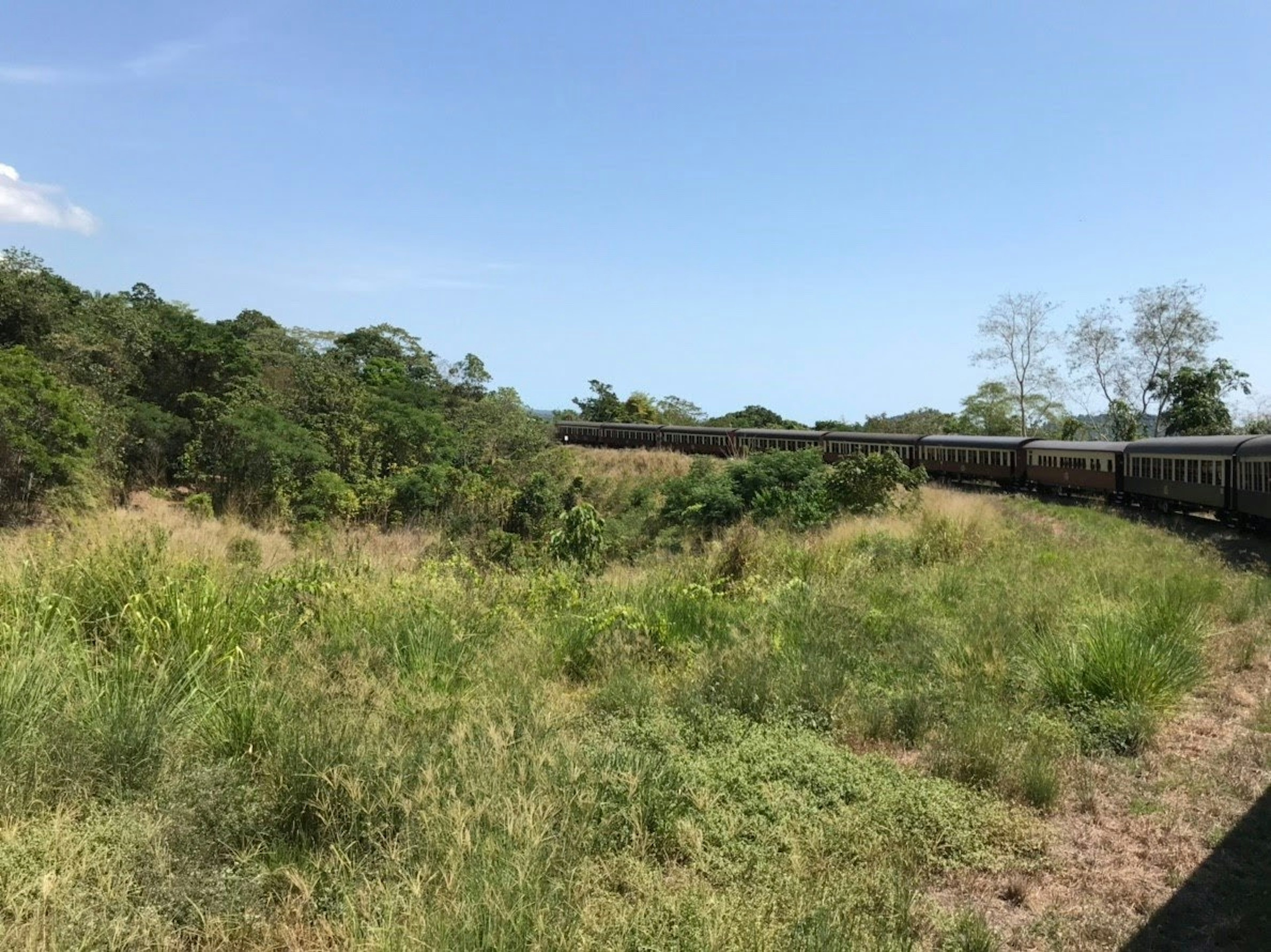 Train sinueux à travers une prairie verdoyante et un ciel bleu