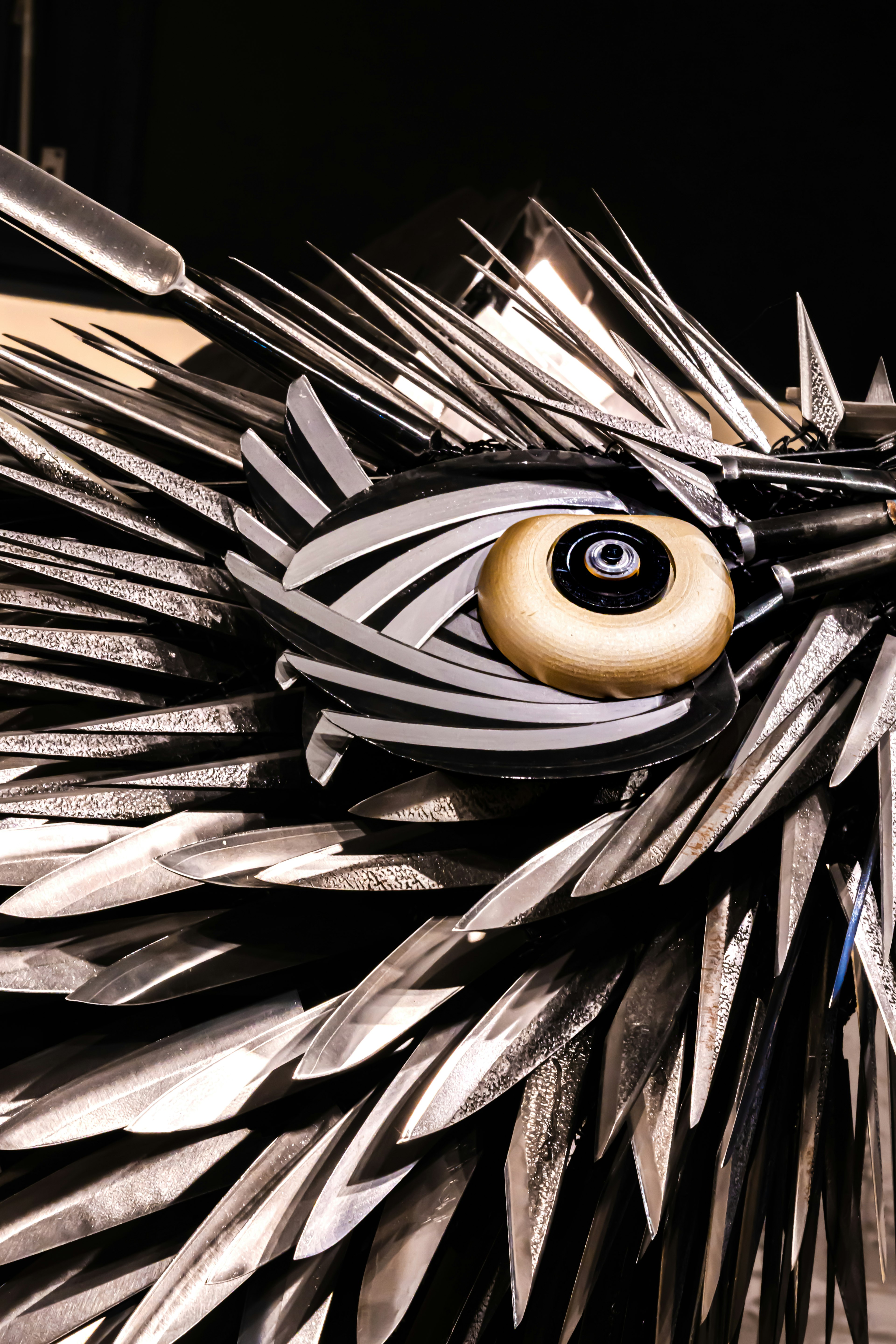 Close-up of a metallic bird sculpture featuring intricate feathers and a striking eye