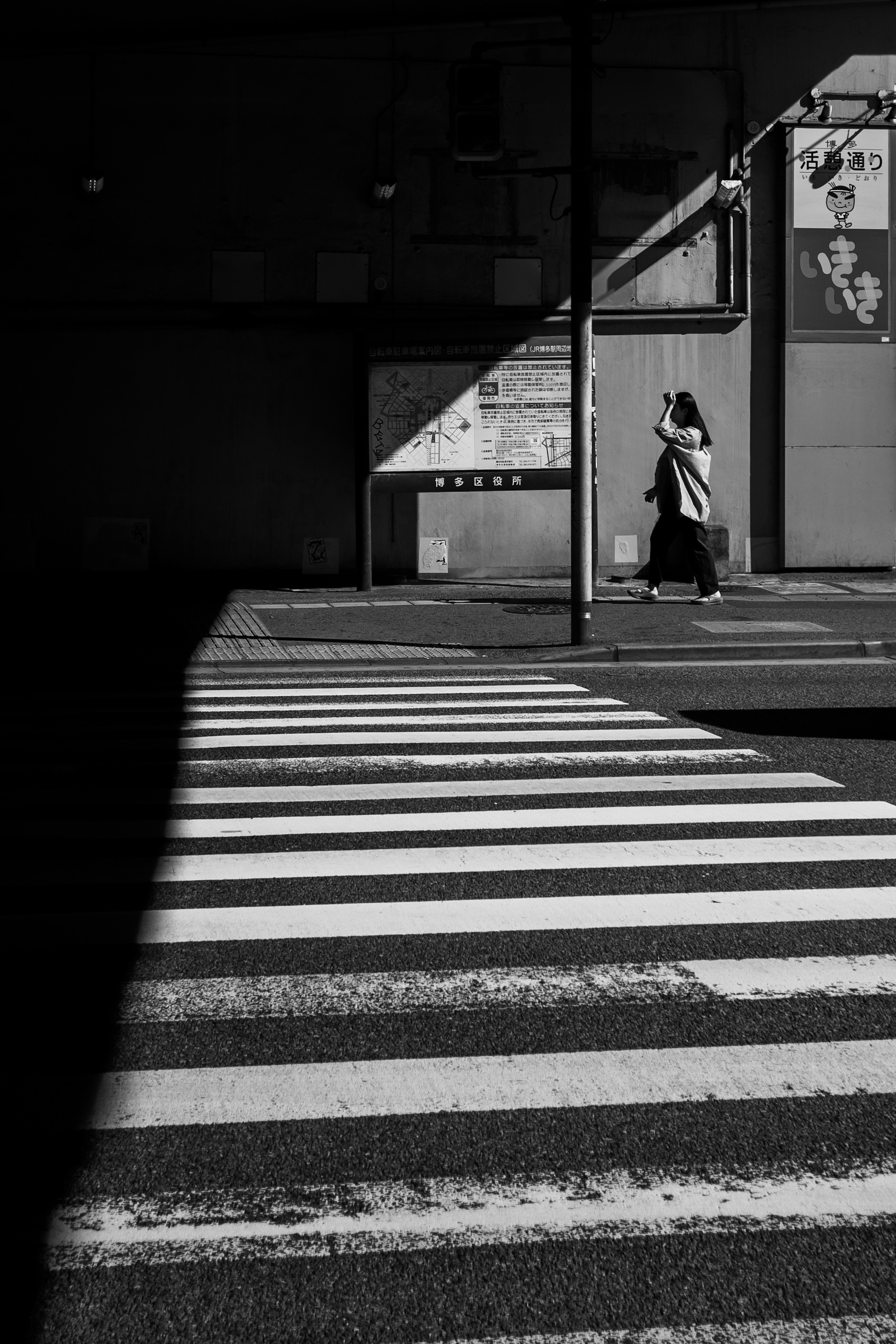 Silueta de una mujer caminando sobre un paso de cebra rayado en blanco y negro