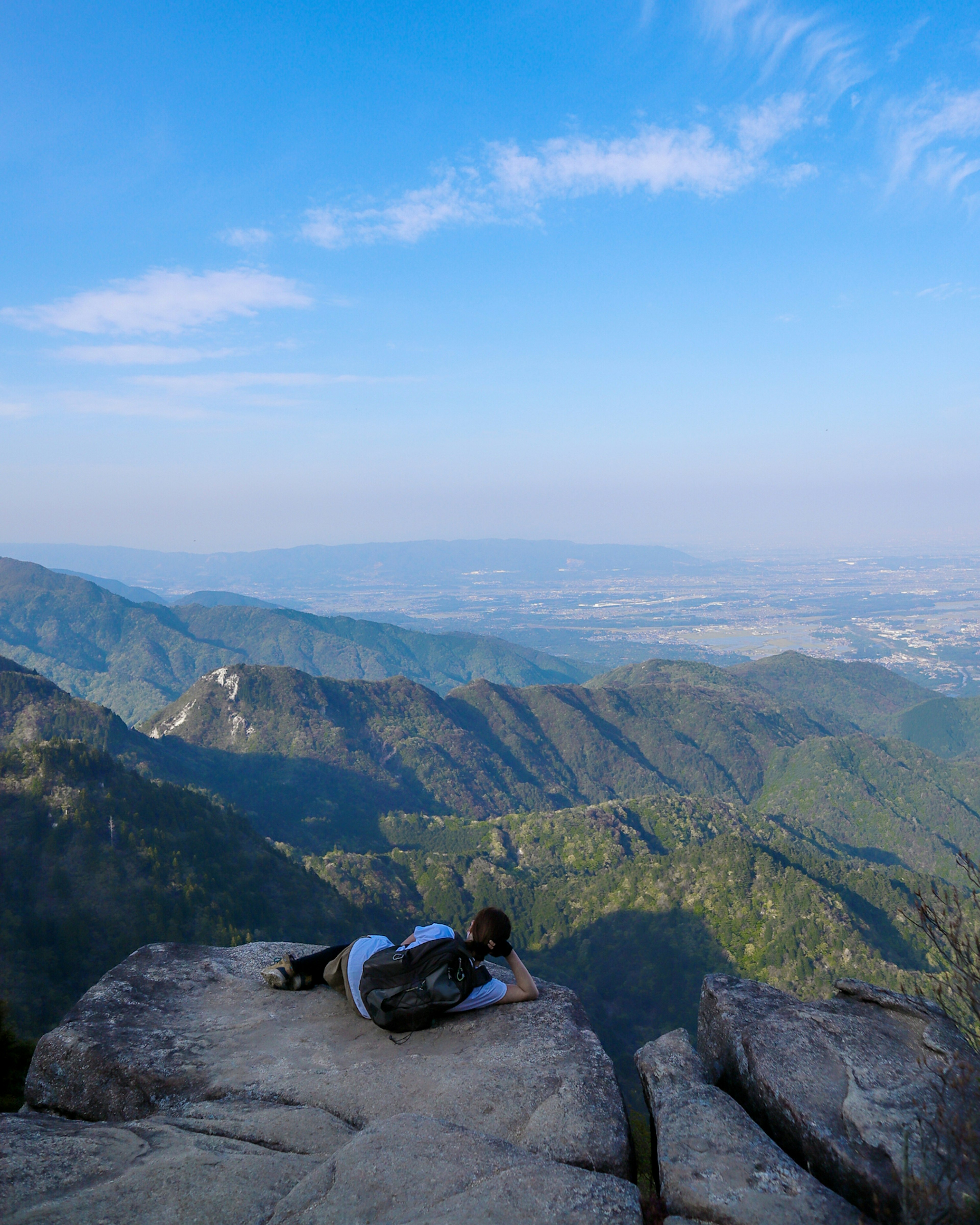 Personne allongée sur un sommet de montagne avec un paysage pittoresque