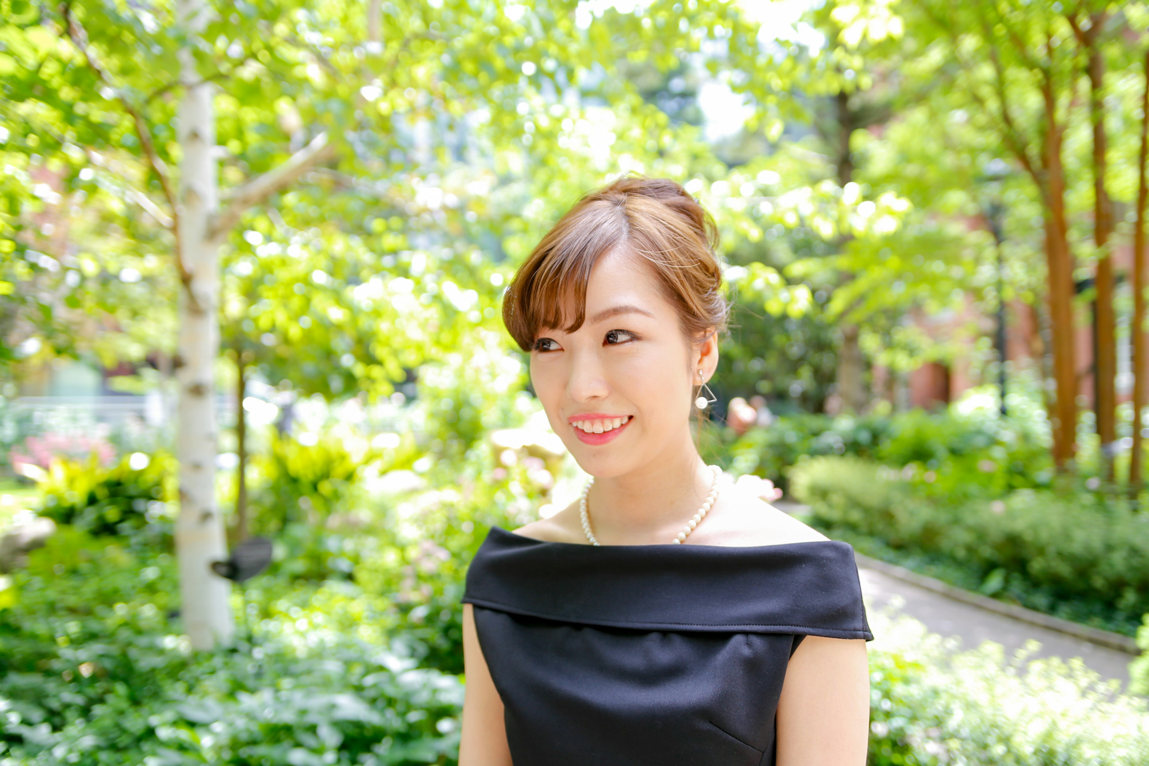 Mujer sonriendo con un vestido negro en un jardín exuberante