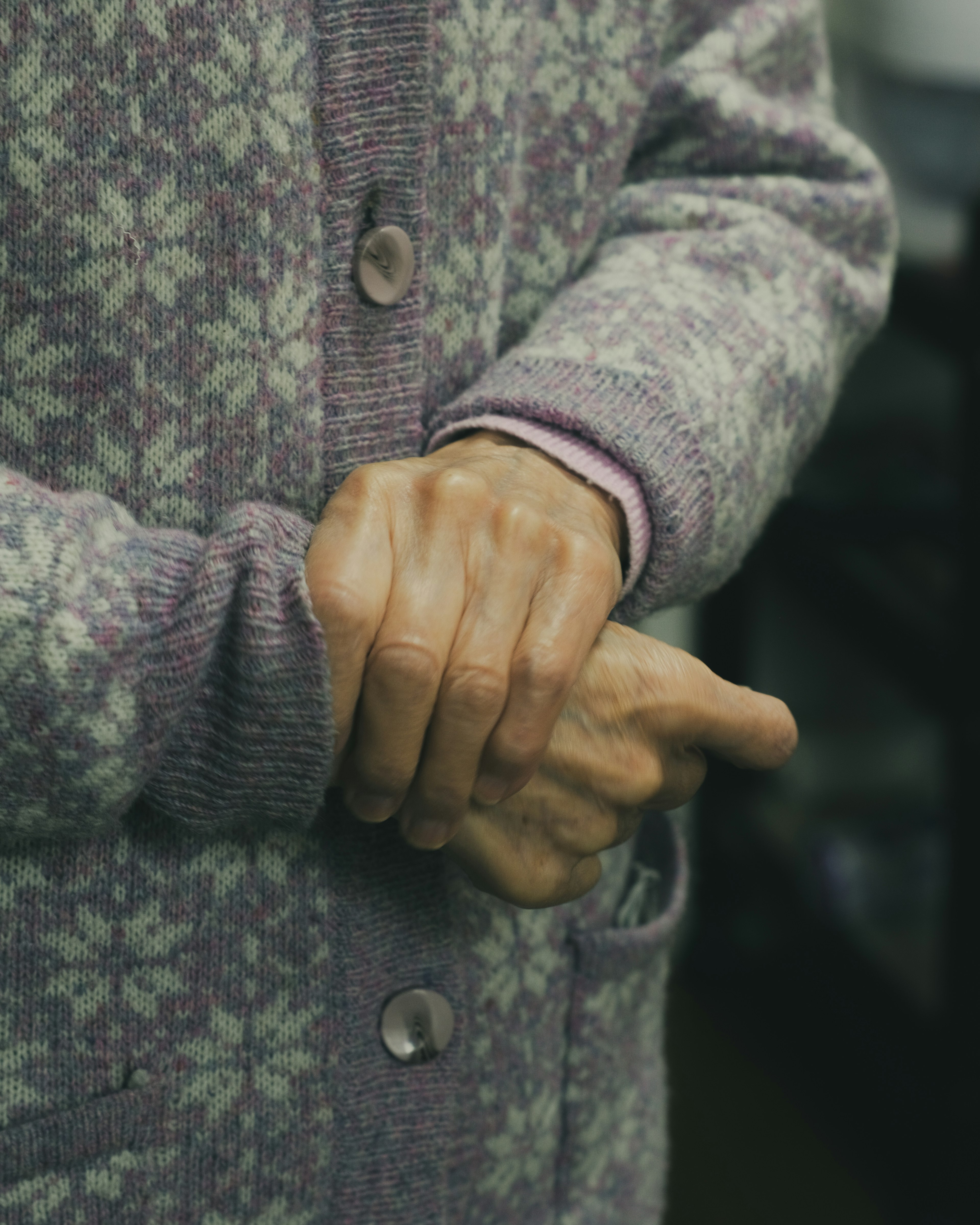 Hands clasped wearing a purple patterned sweater