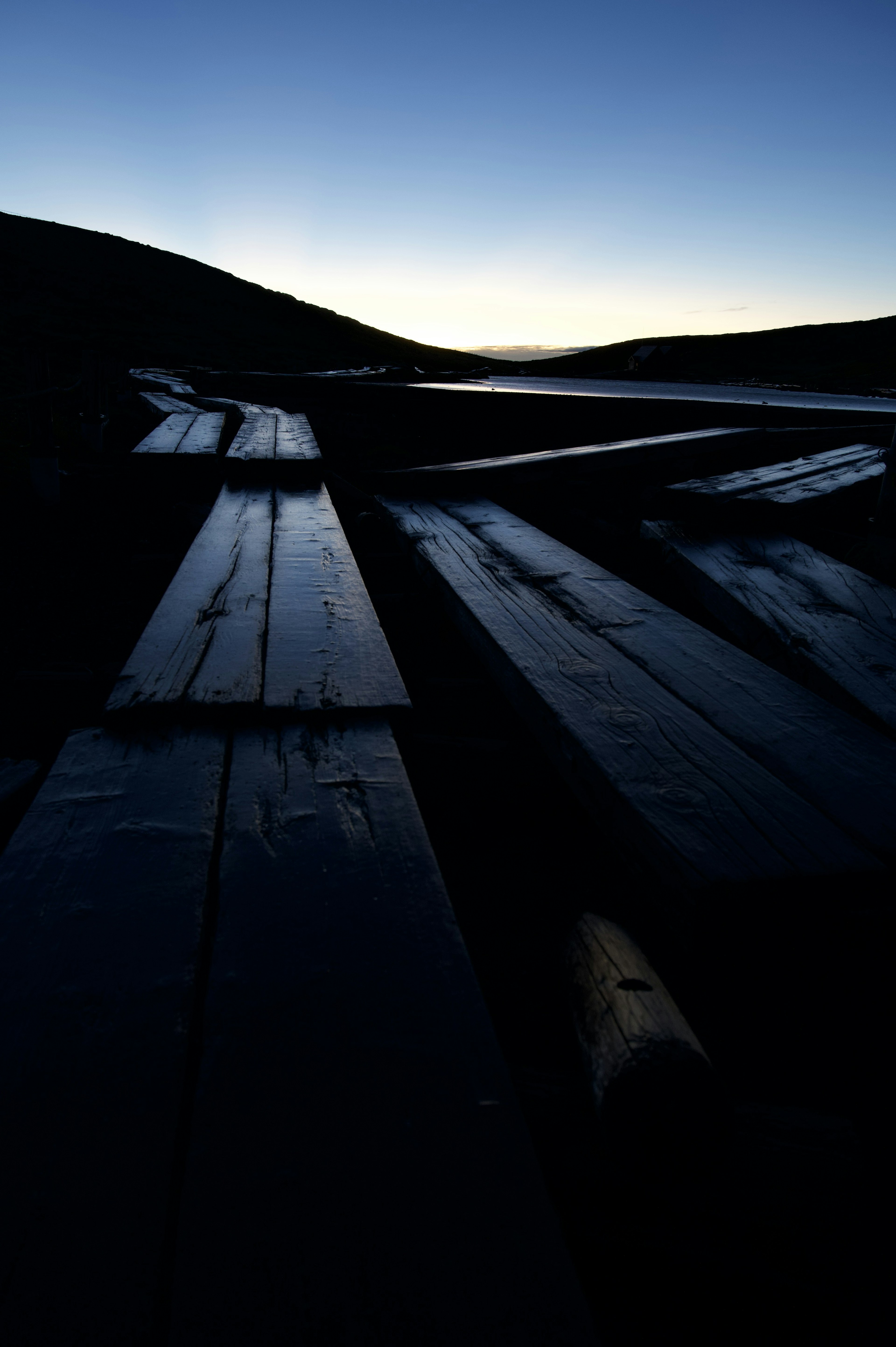 Filas de tablas de madera en el crepúsculo con silueta de colina