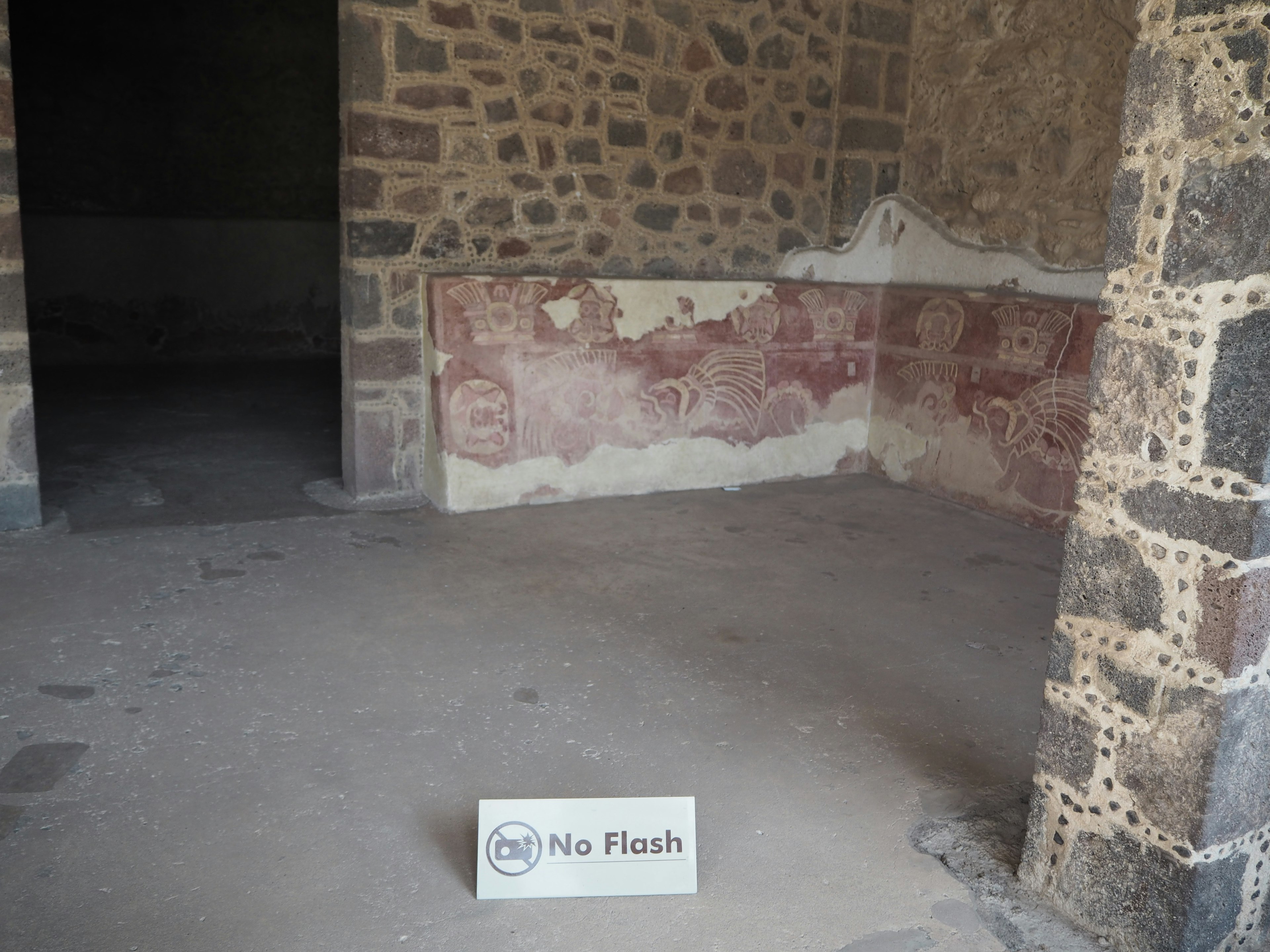 Interior de una antigua habitación de piedra con decoraciones murales rojas desvanecidas