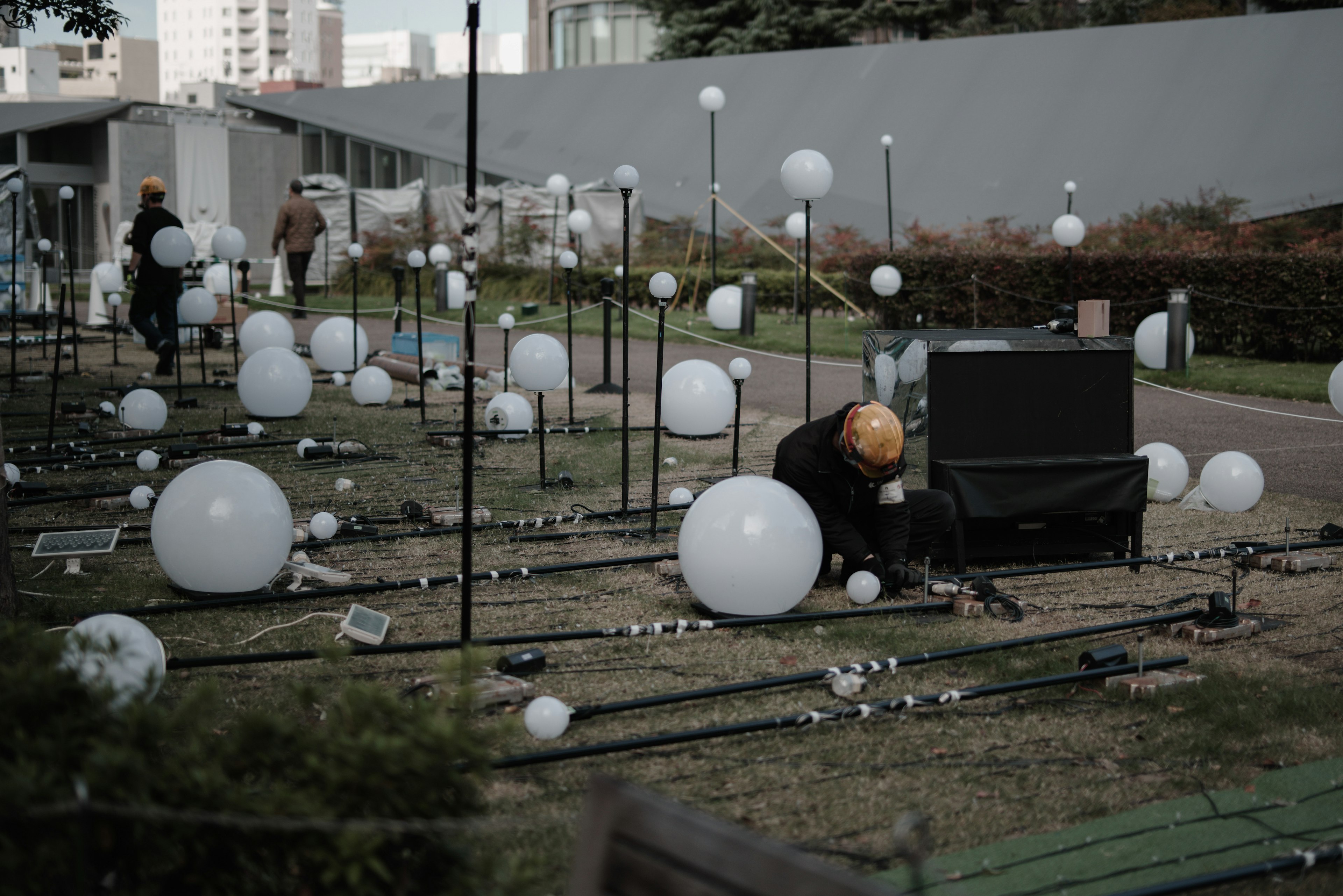 A landscape with white spherical lights and a worker in a park