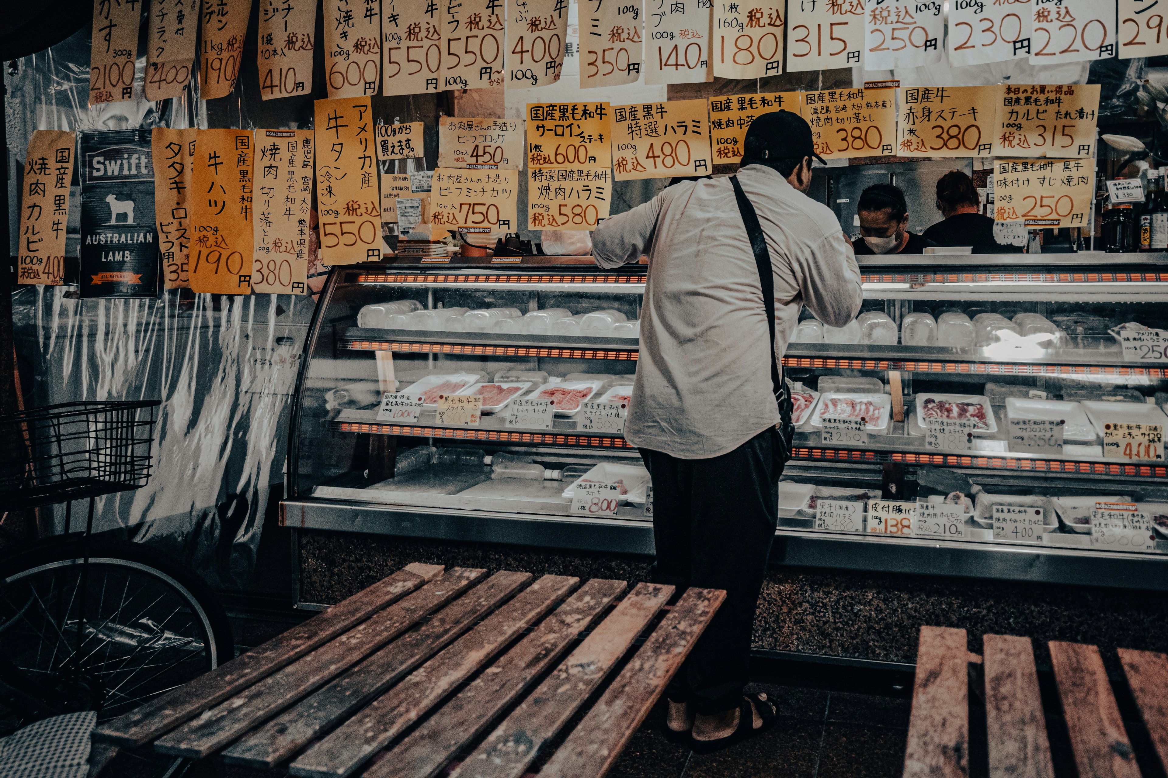 A person selecting food at a street vendor with menus displayed on the wall