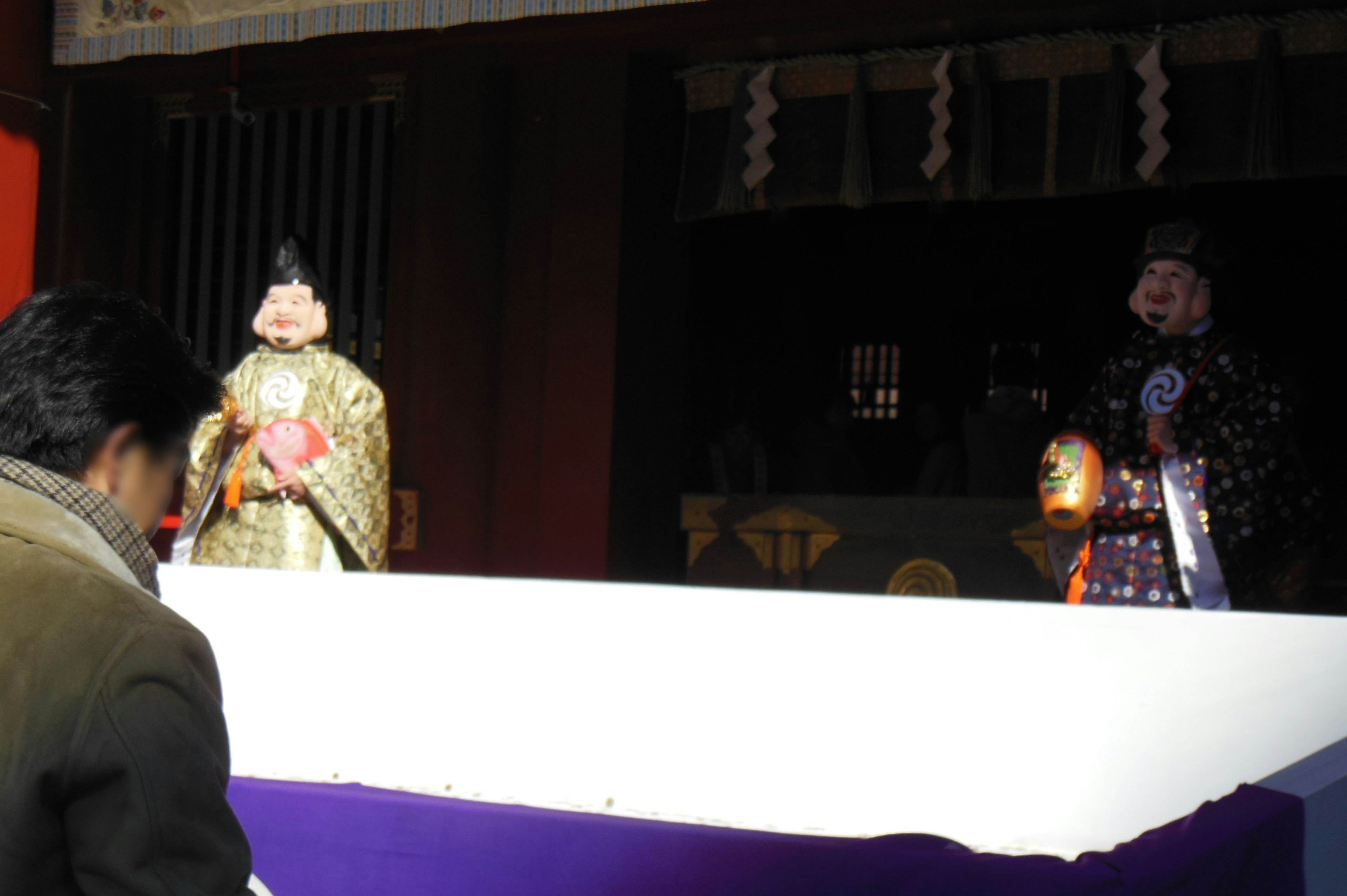 Escena de marionetas tradicionales en un escenario con un espectador