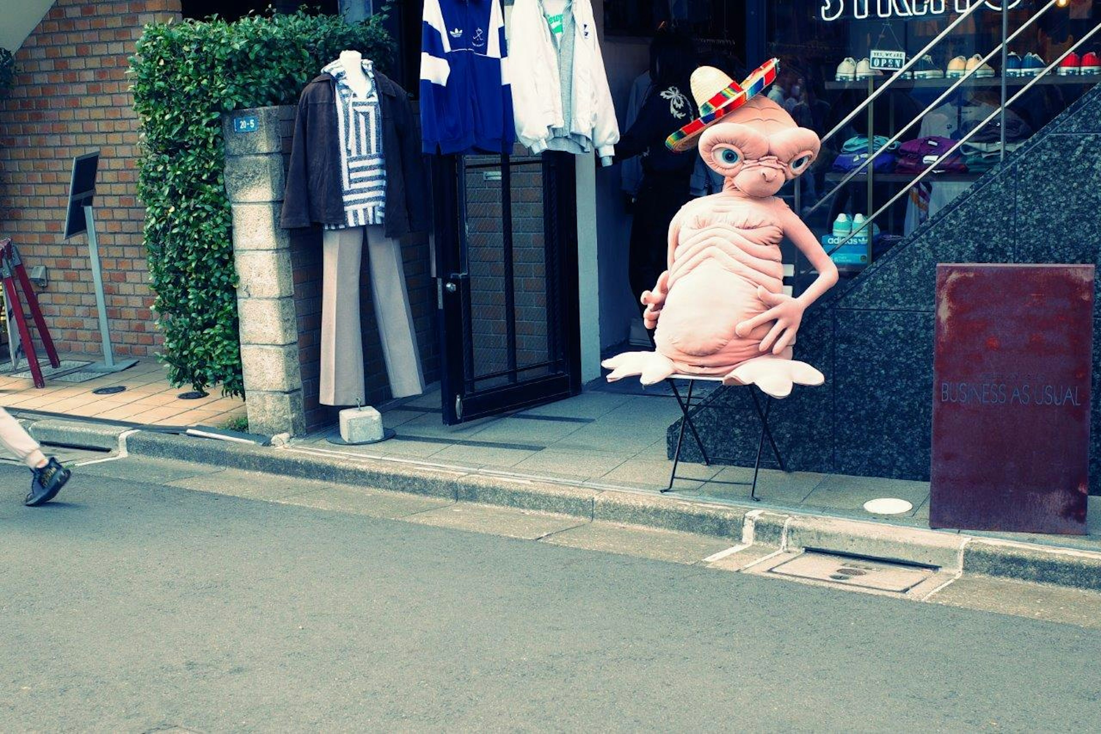 Un personnage mascotte rose portant un chapeau devant un magasin