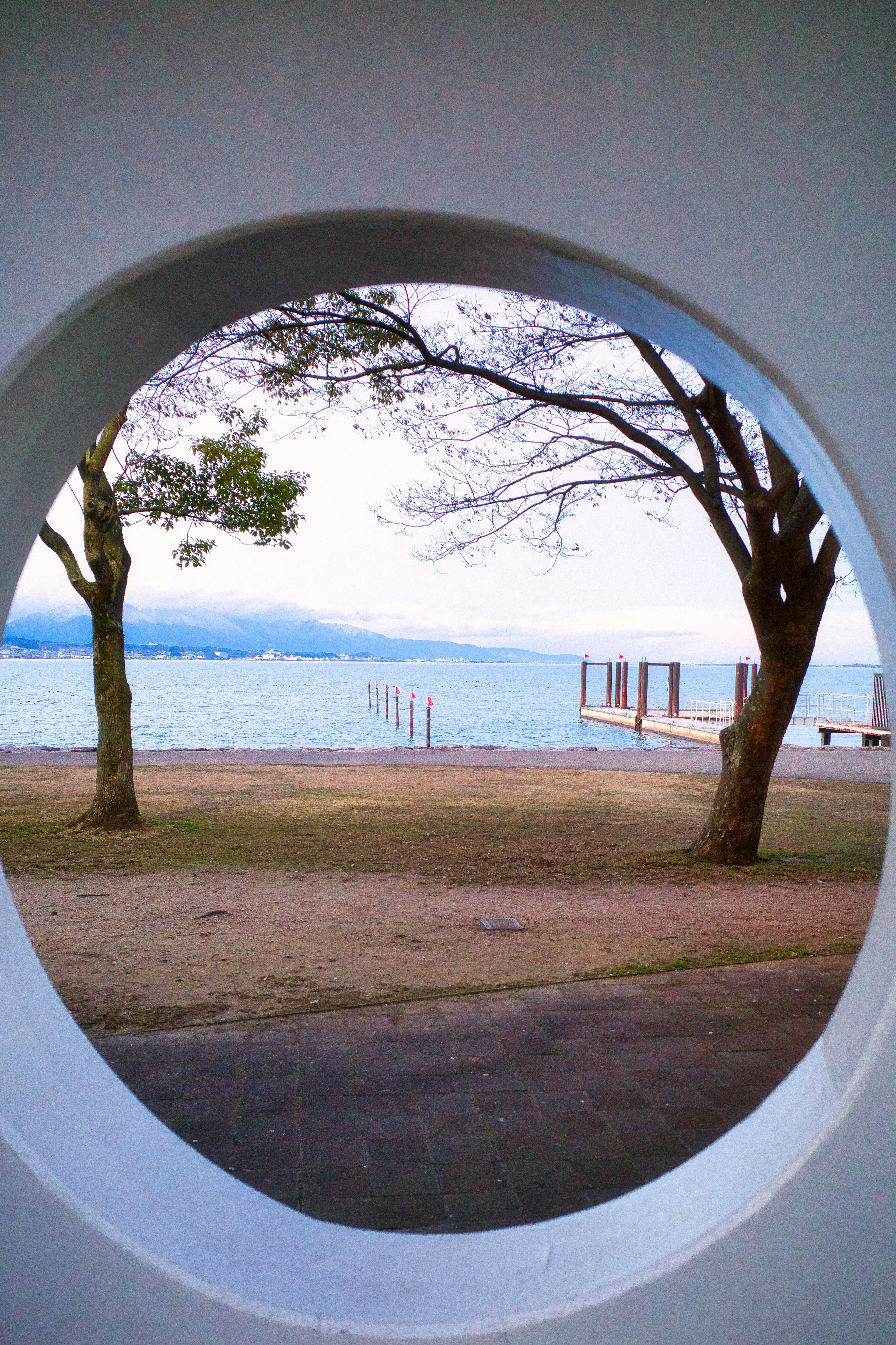 円形の窓から見える湖と木々の風景