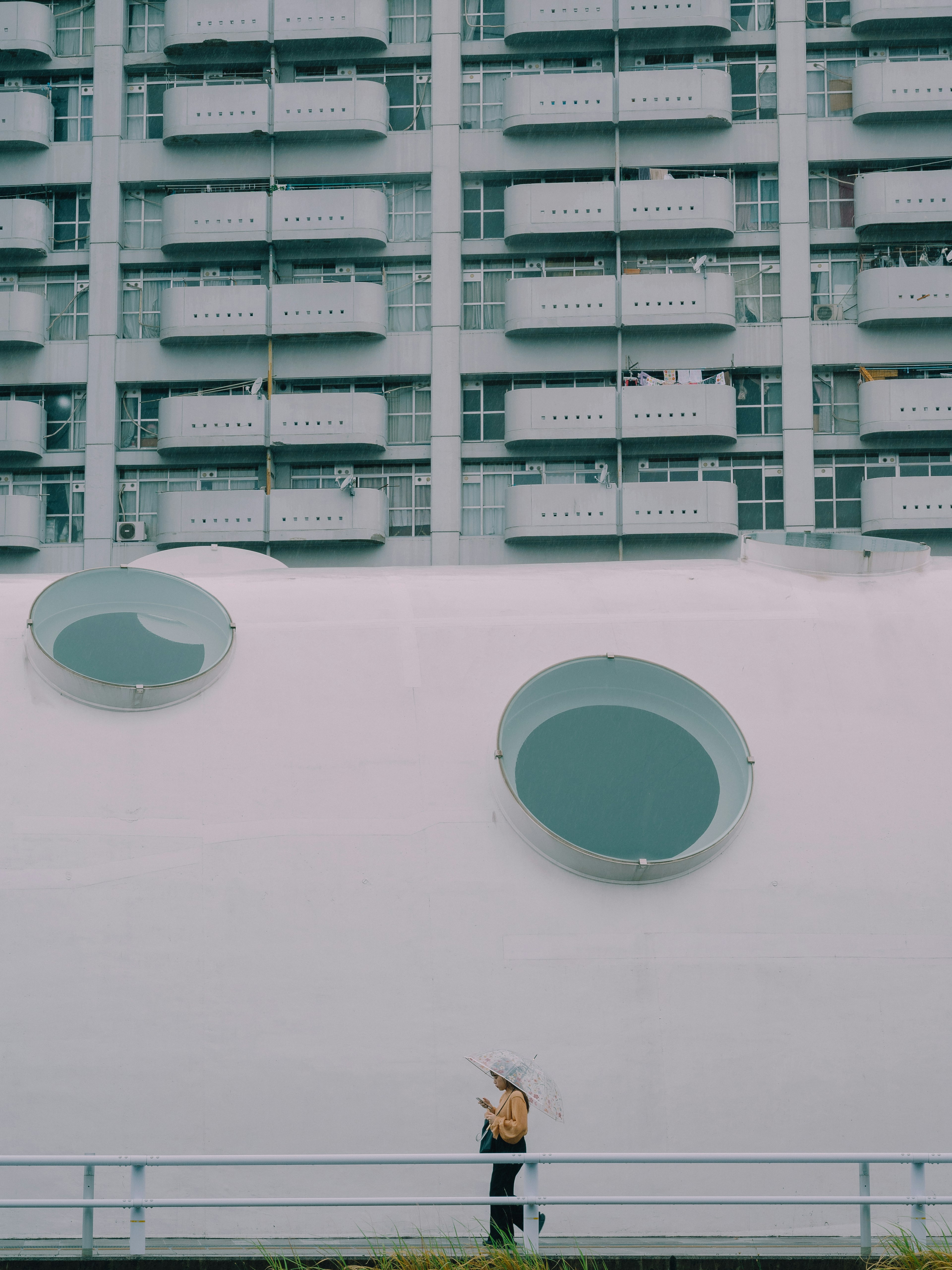 A person walking in front of a modern building with circular windows