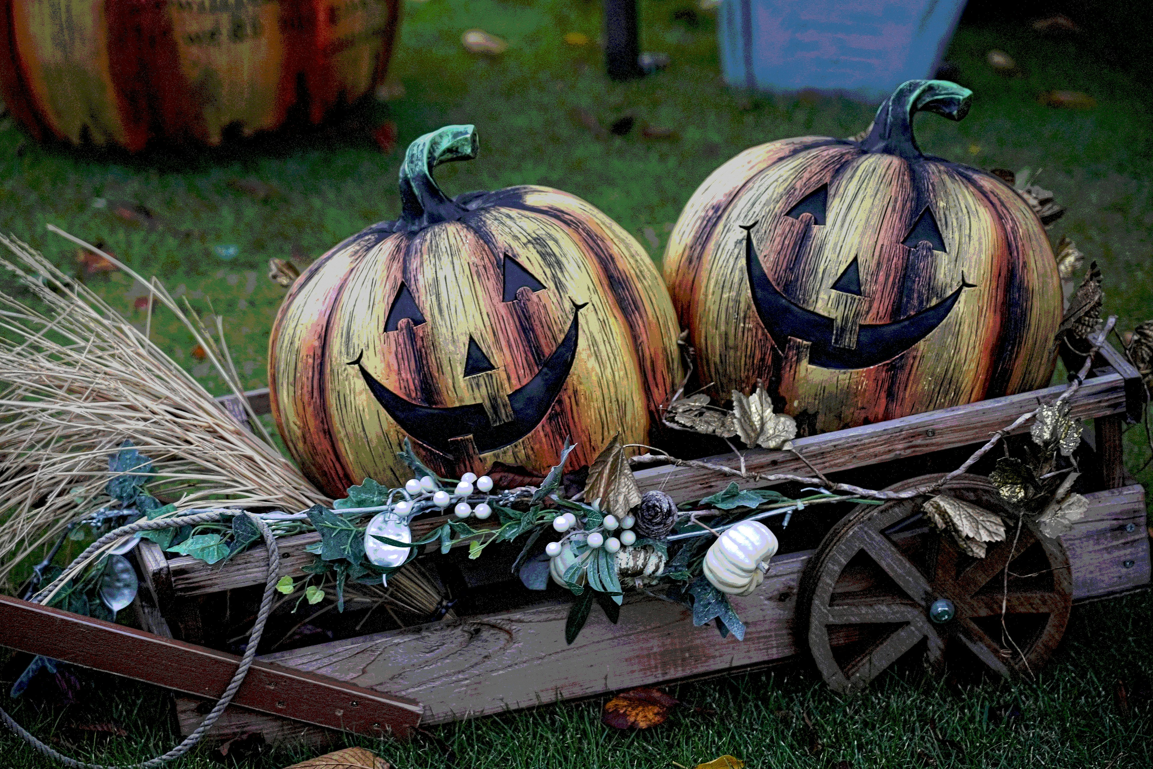 Due zucche decorate per Halloween su un carretto di legno con fogliame