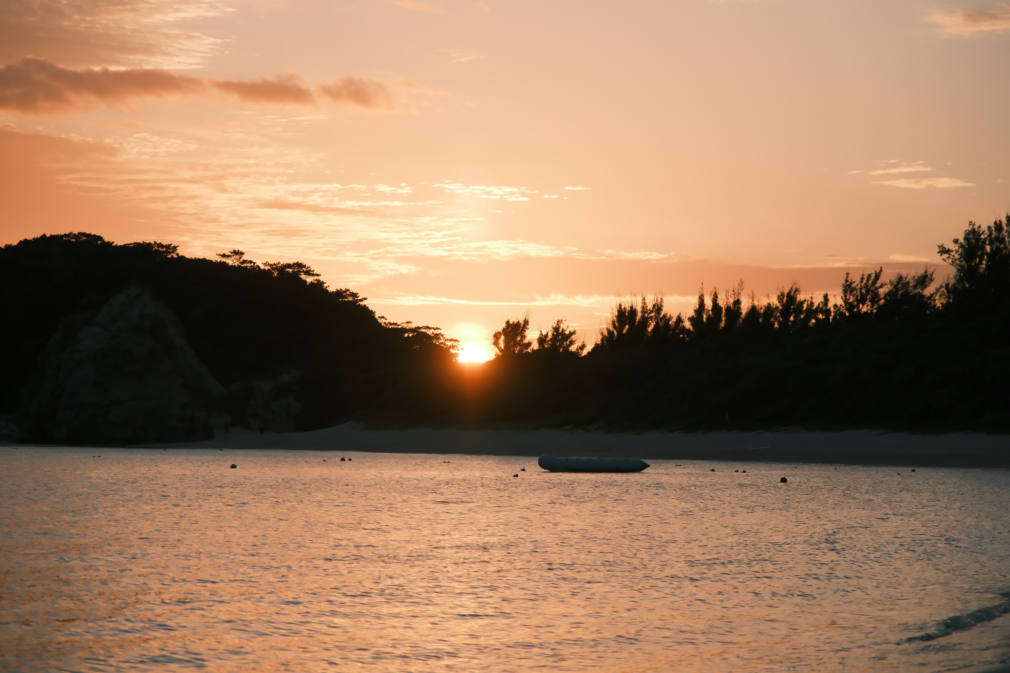 Beach scene at sunset with a small boat on the water