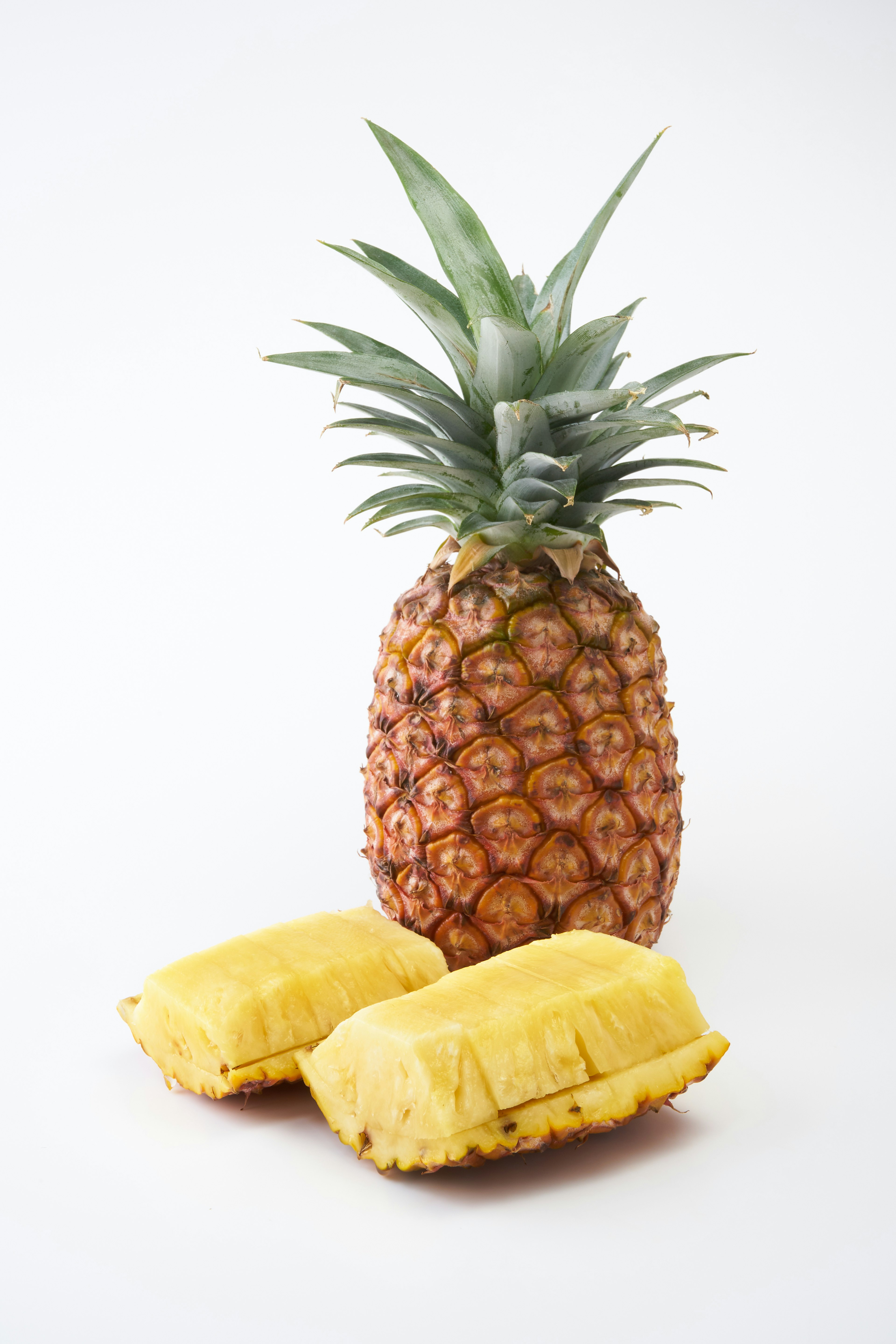 A pineapple with two pieces of mango flesh beside it