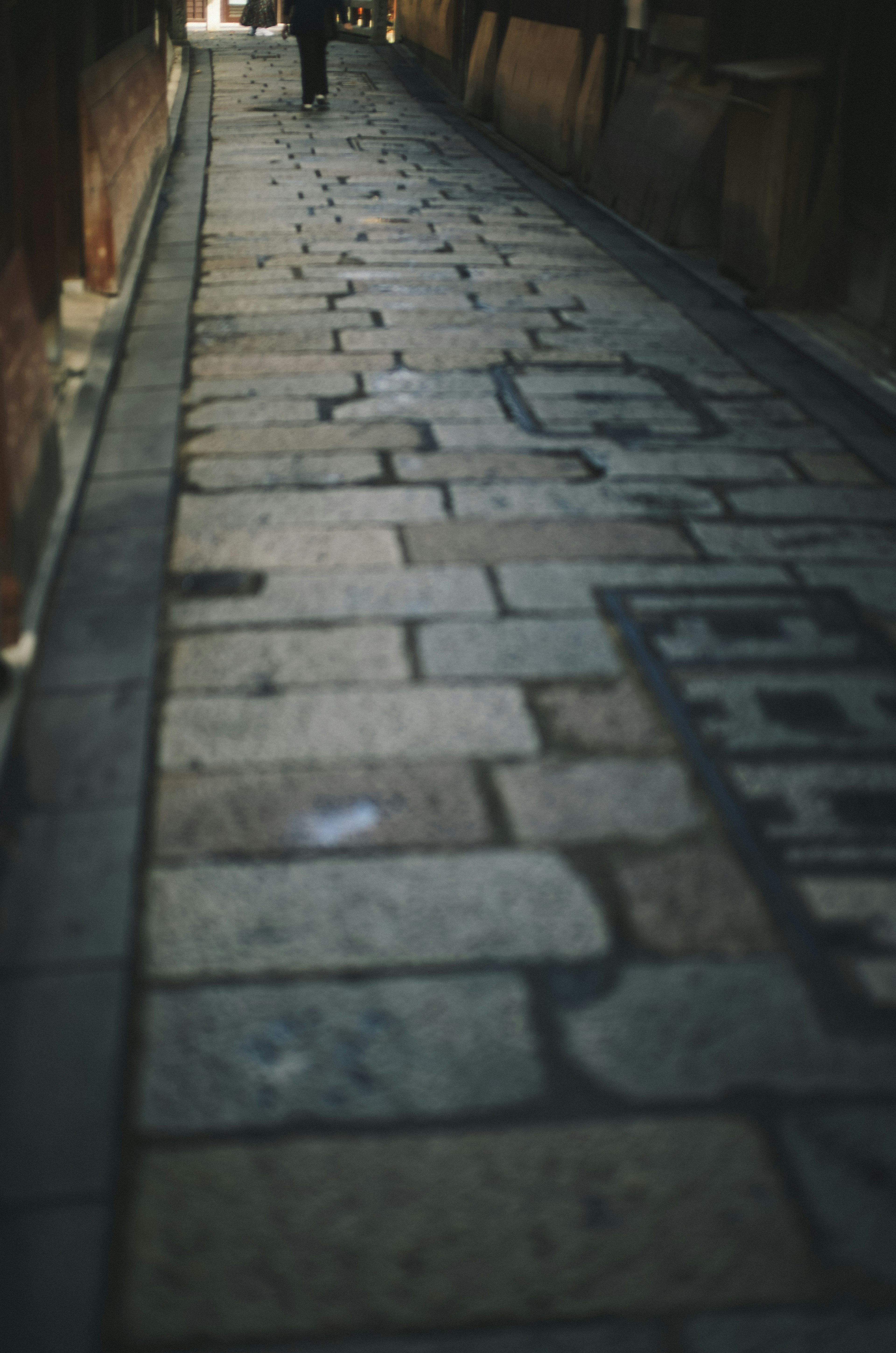 A cobblestone alleyway with a person walking