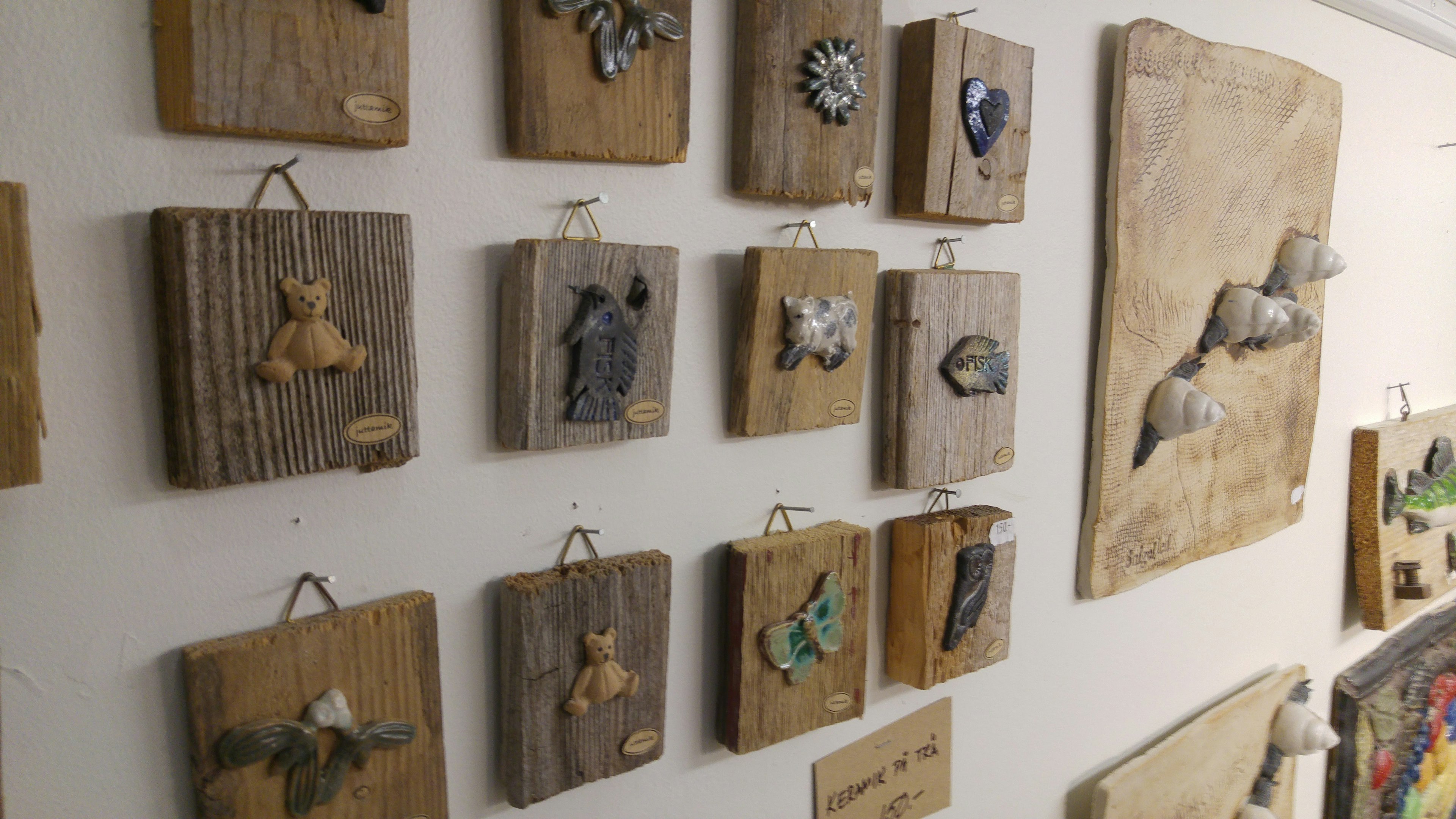 Una colección de piezas de arte en madera exhibidas en una pared con motivos de animales y naturaleza