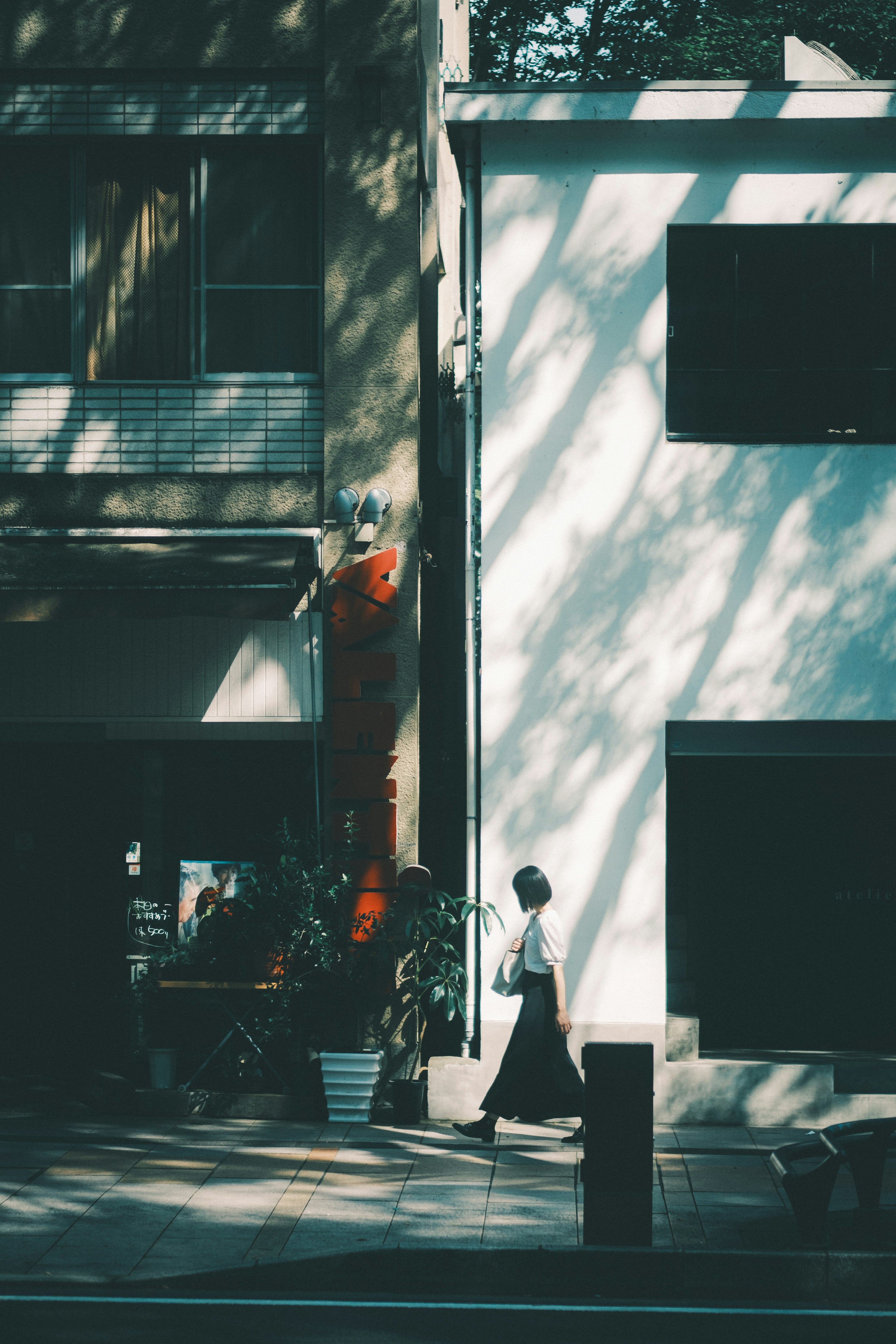 Woman walking in an urban setting with a white wall and shadows