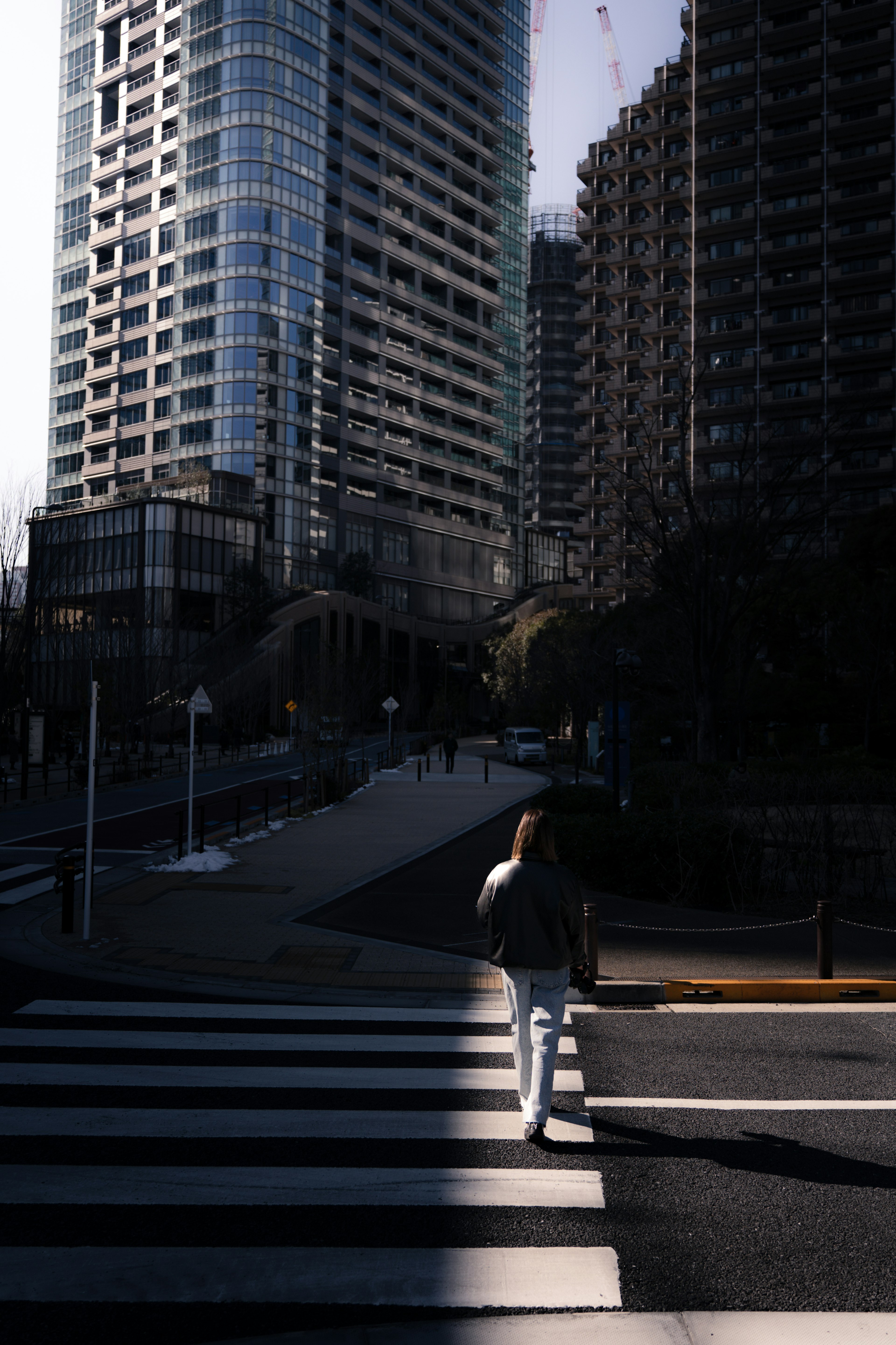 A person walking through a crosswalk surrounded by tall buildings