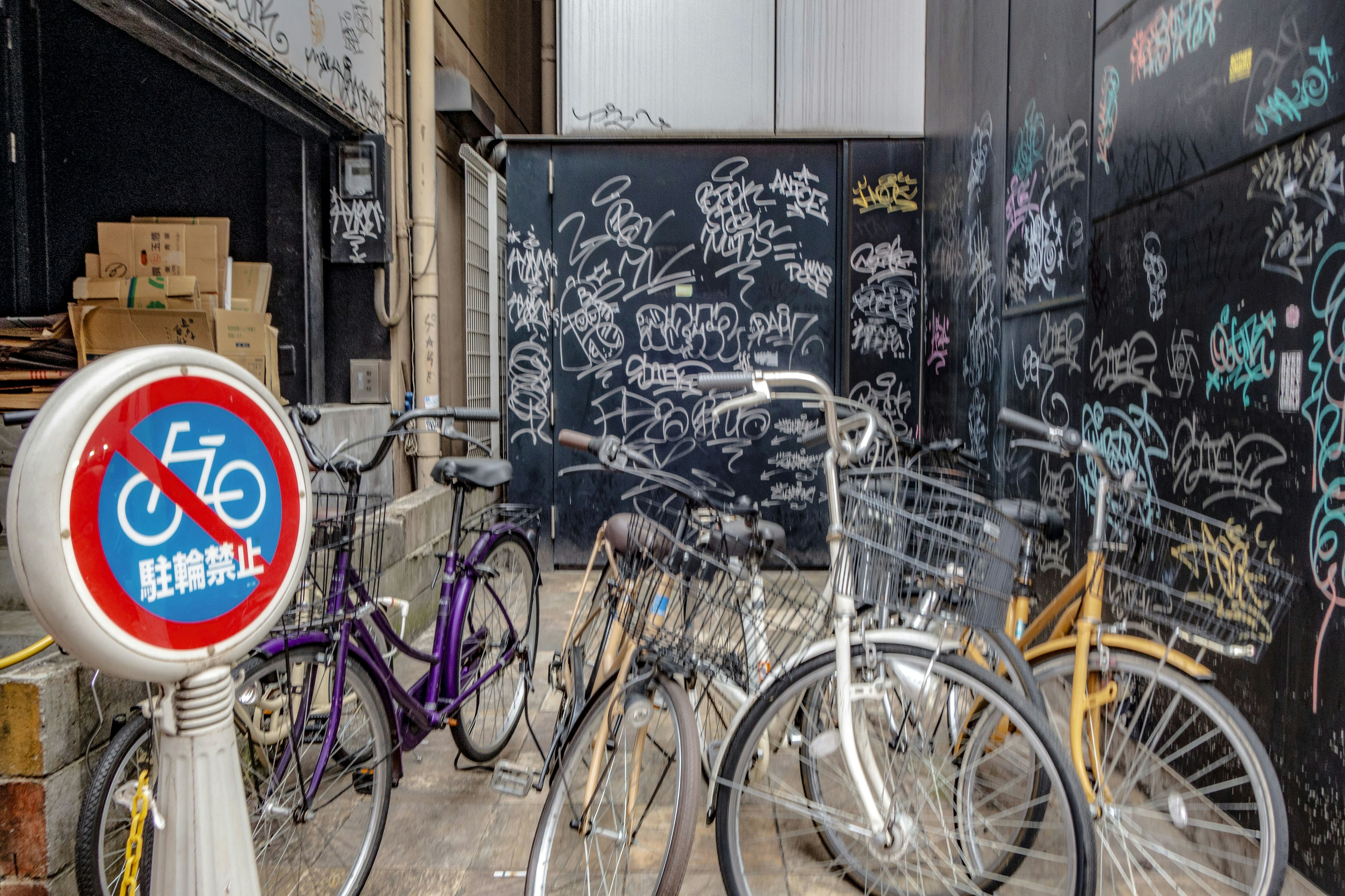 Narrow alley with bicycles and a graffiti-covered wall