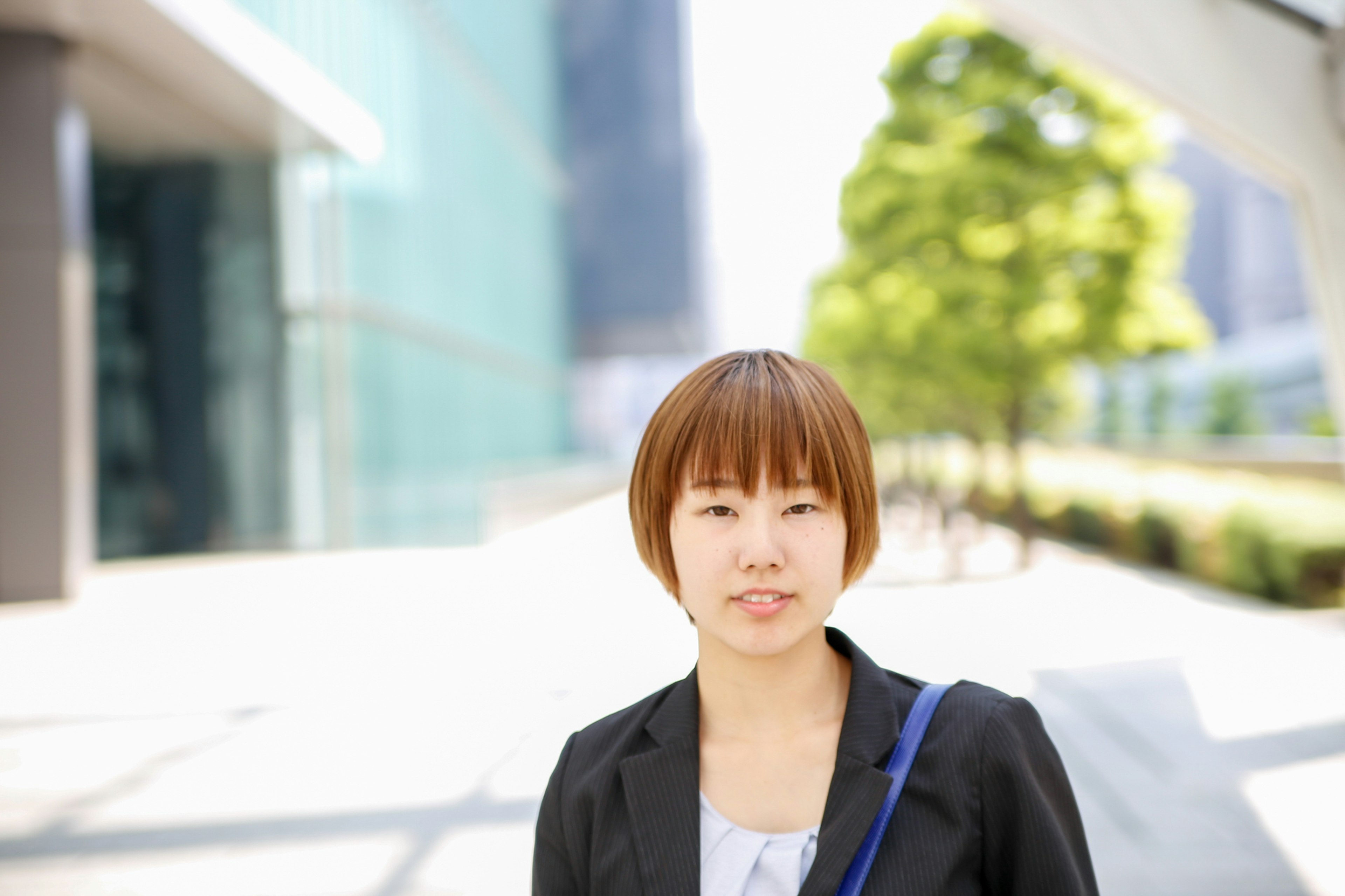 밝은 배경 앞에 서 있는 여성의 초상 짧은 헤어스타일과 비즈니스 정장 착용