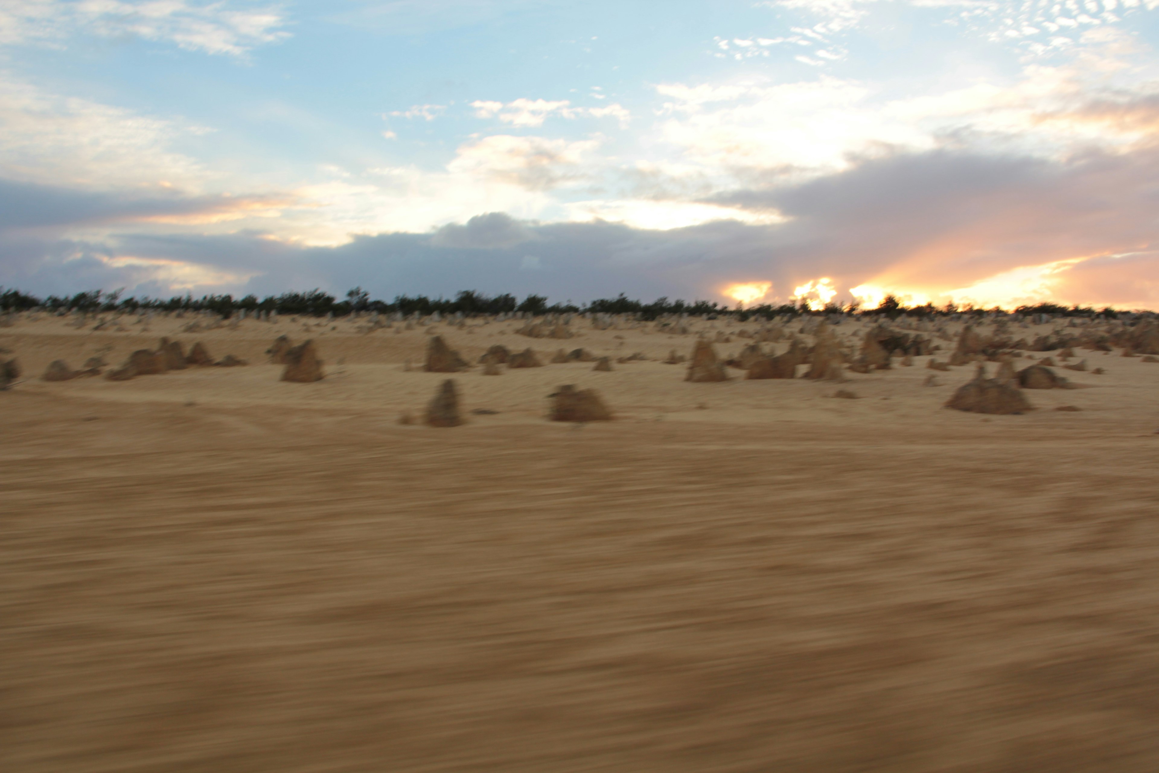 Un paisaje con dunas de arena y un atardecer colorido