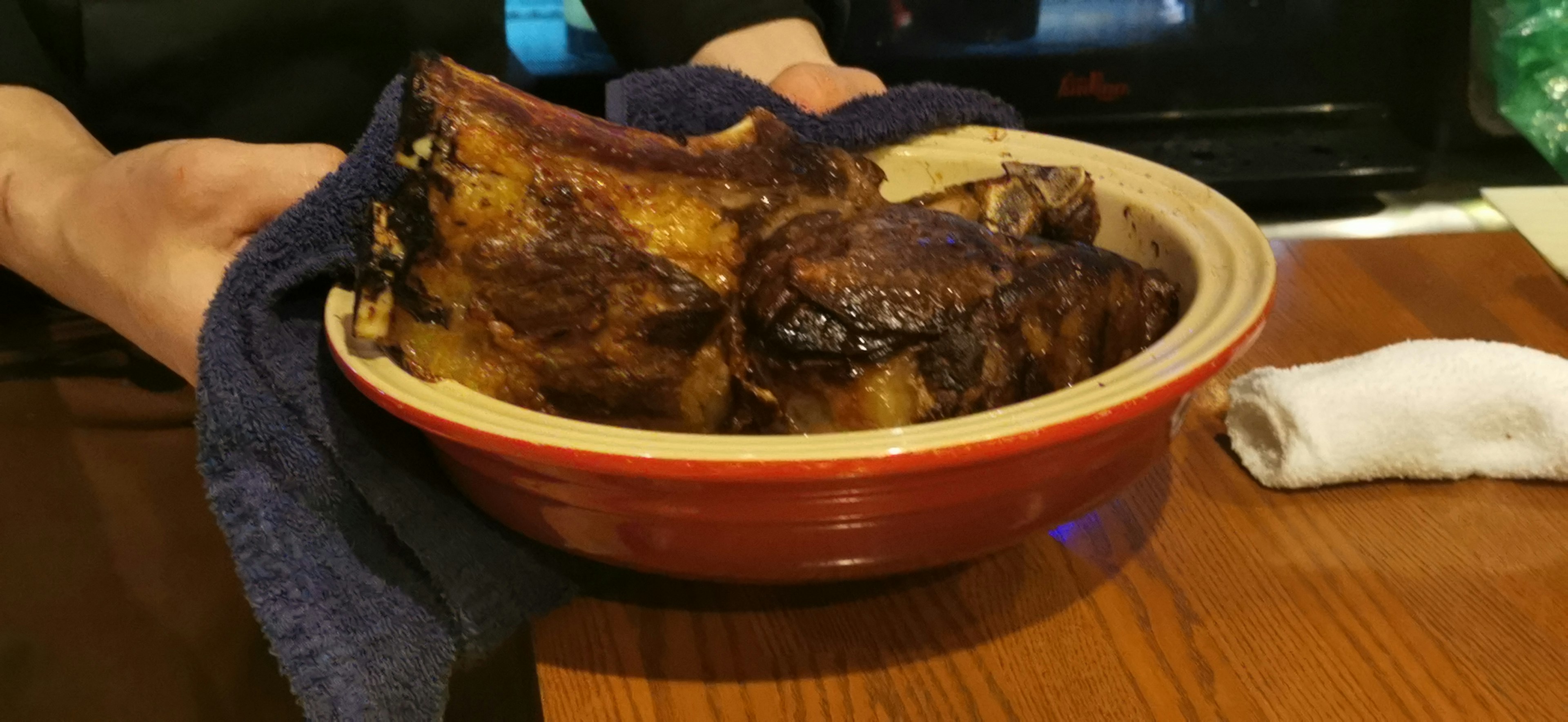 Manos sosteniendo un bol de carne a la parrilla bien presentada