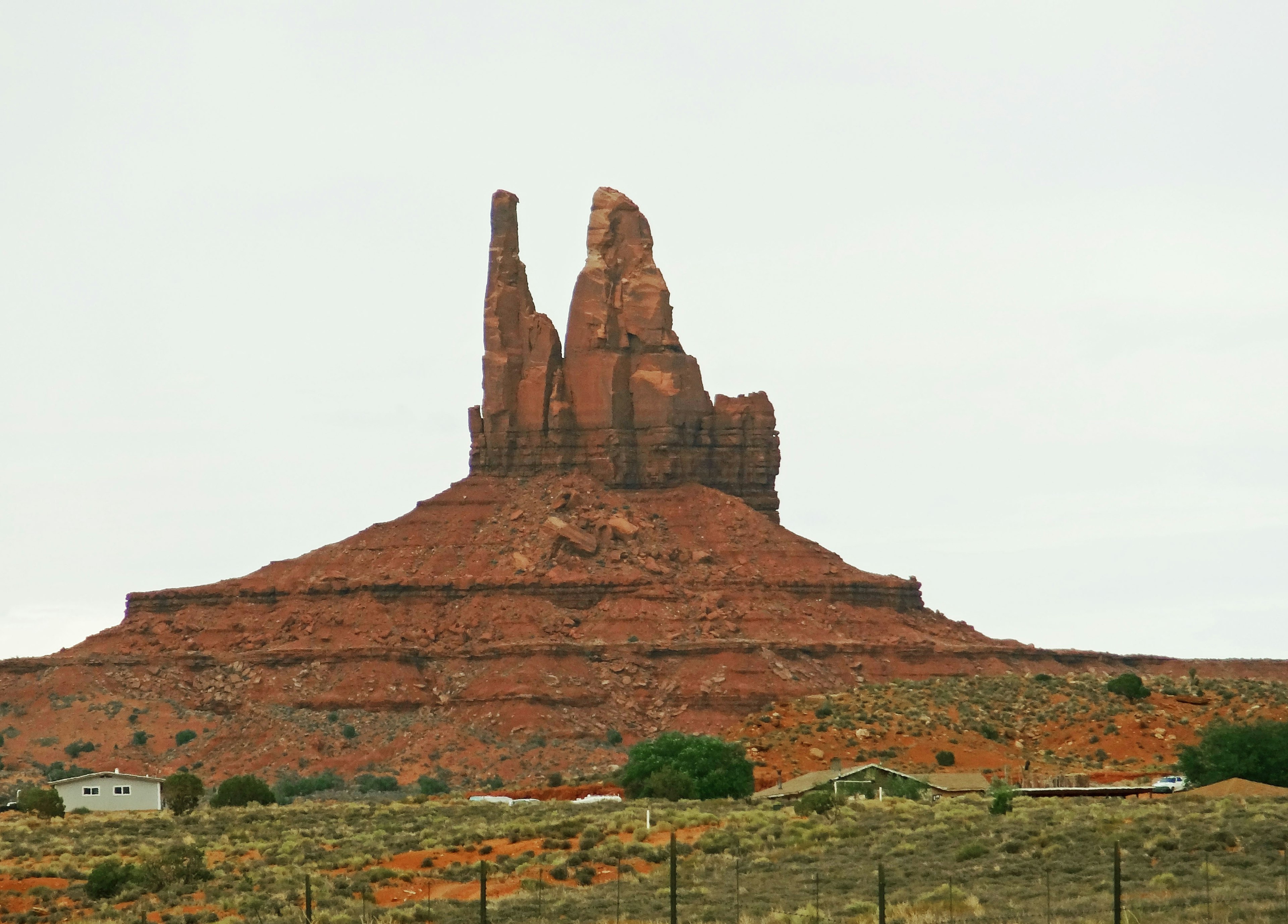 Lanskap Monument Valley dengan formasi batu merah dan vegetasi hijau