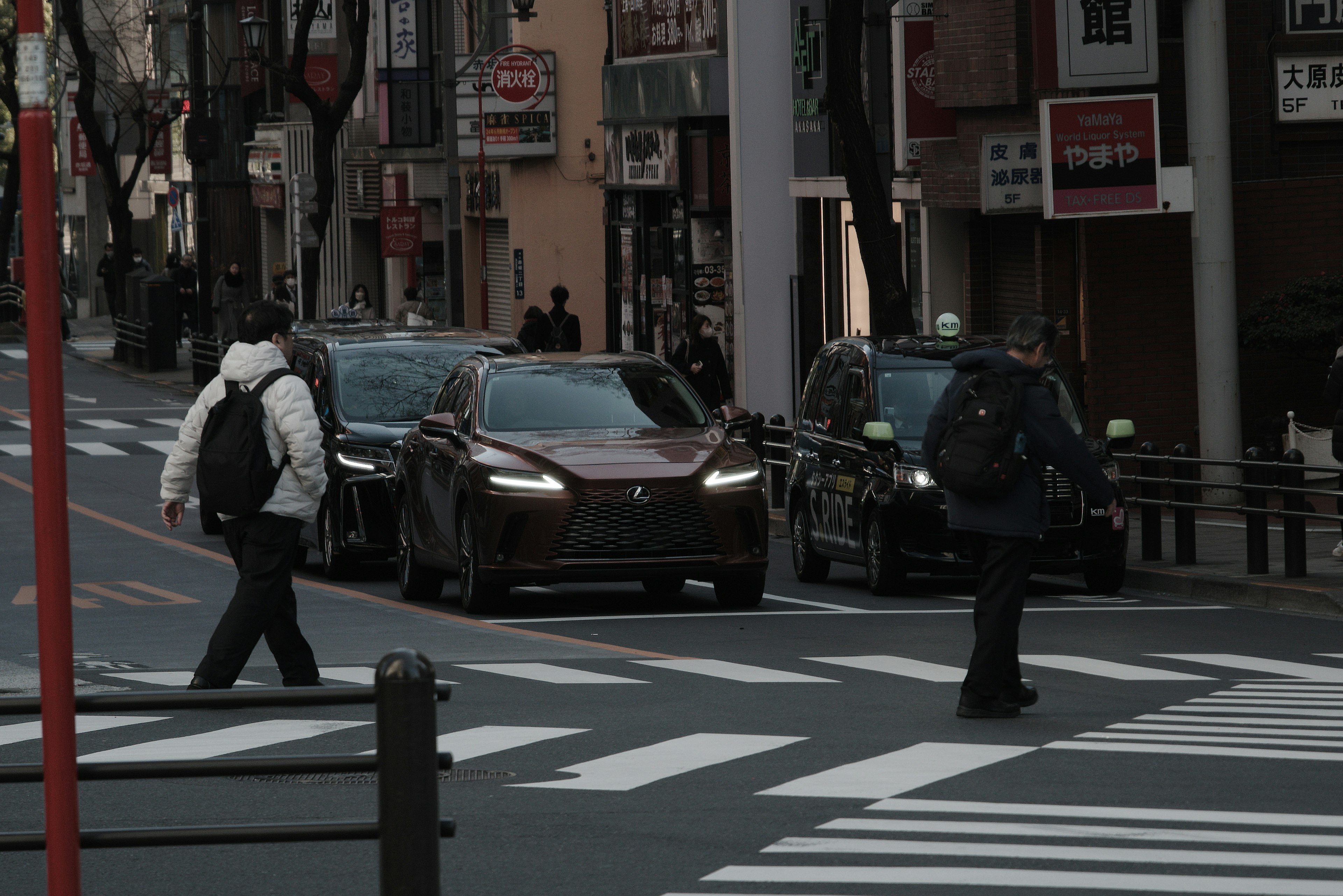 Scène urbaine avec des personnes traversant la rue et des voitures passant