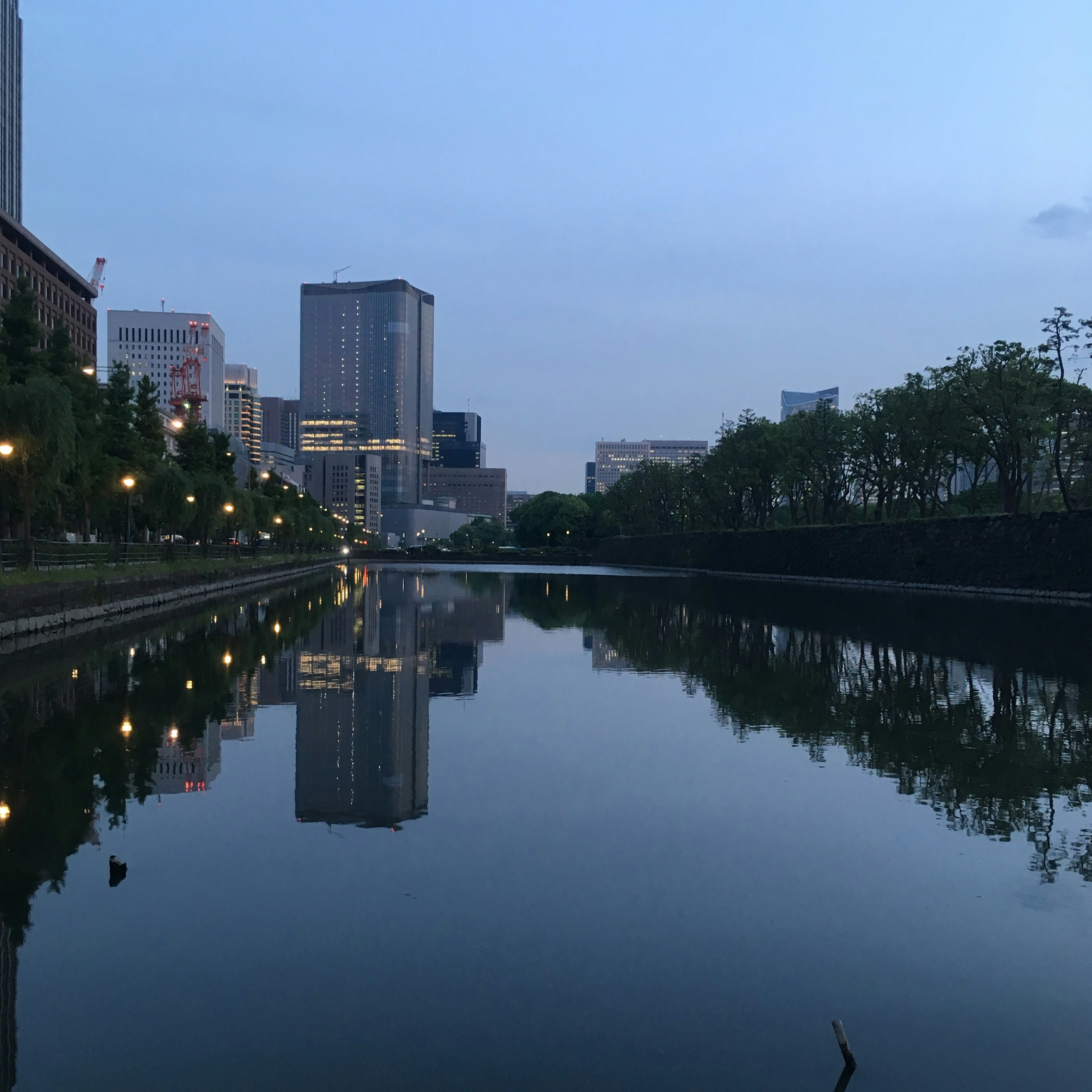 Stadtlandschaft, die sich im ruhigen Wasser bei Dämmerung mit Lichtern spiegelt