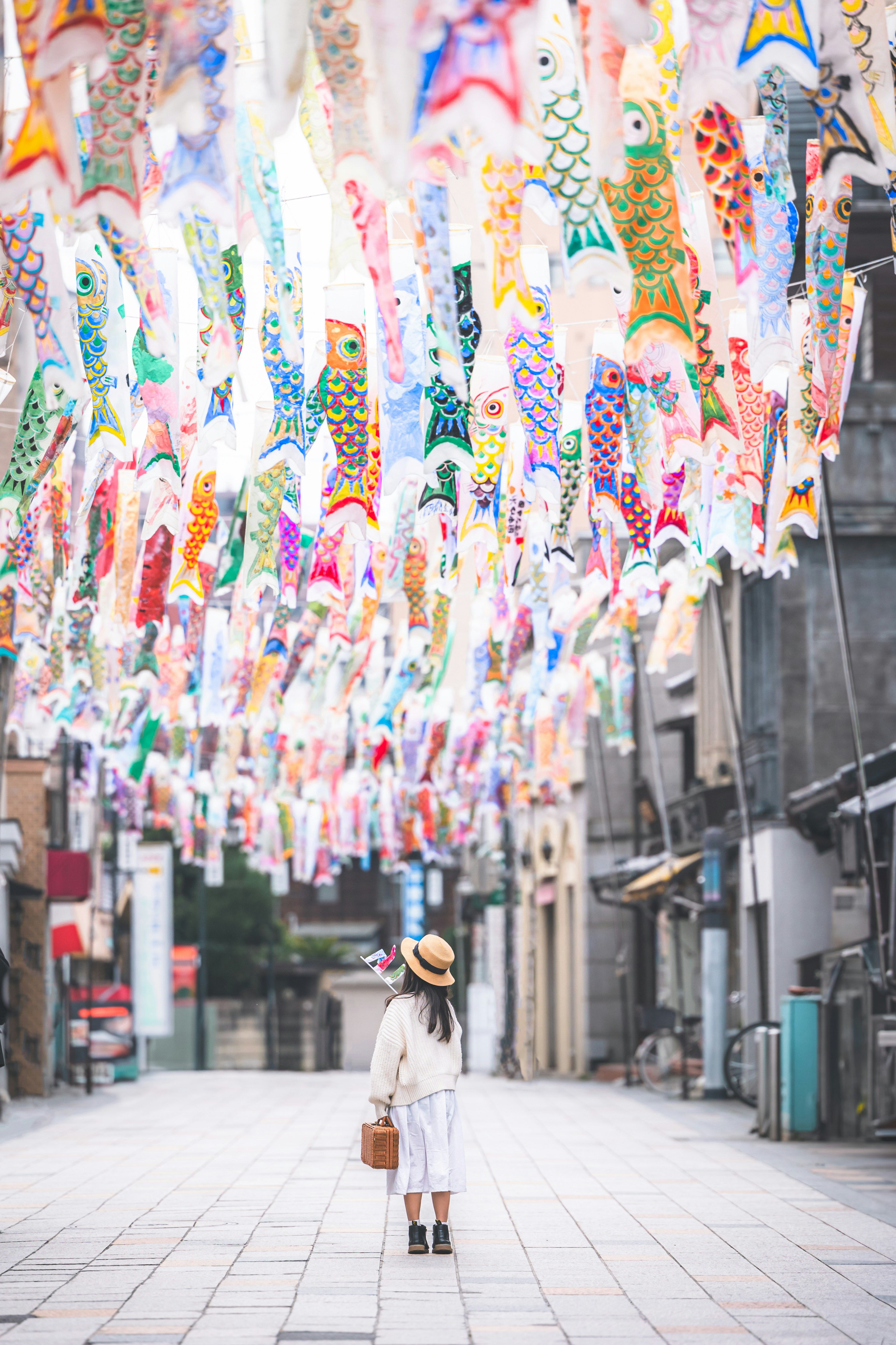 Una ragazza in piedi in una strada decorata con koinobori colorati