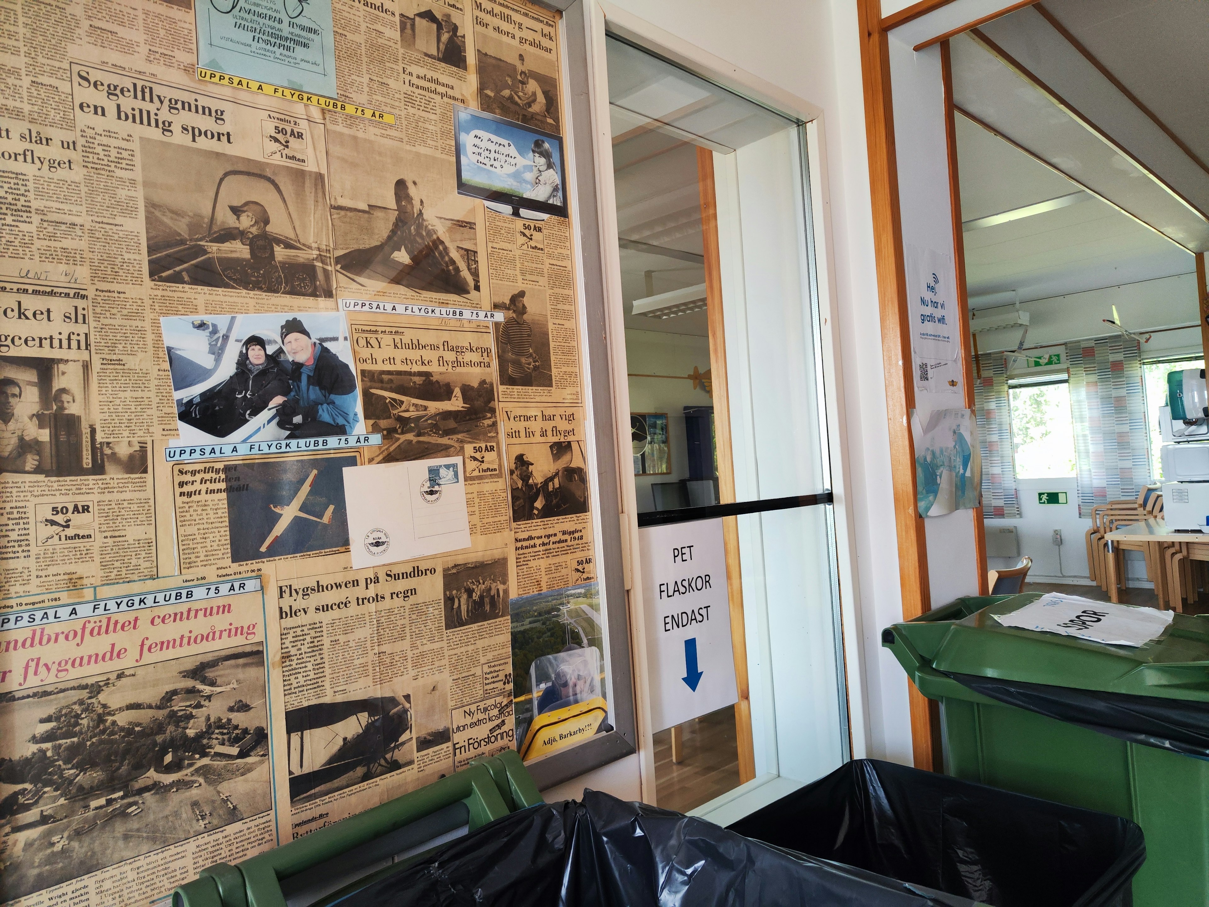 Interior de una habitación con recortes de periódicos antiguos y fotos en la pared