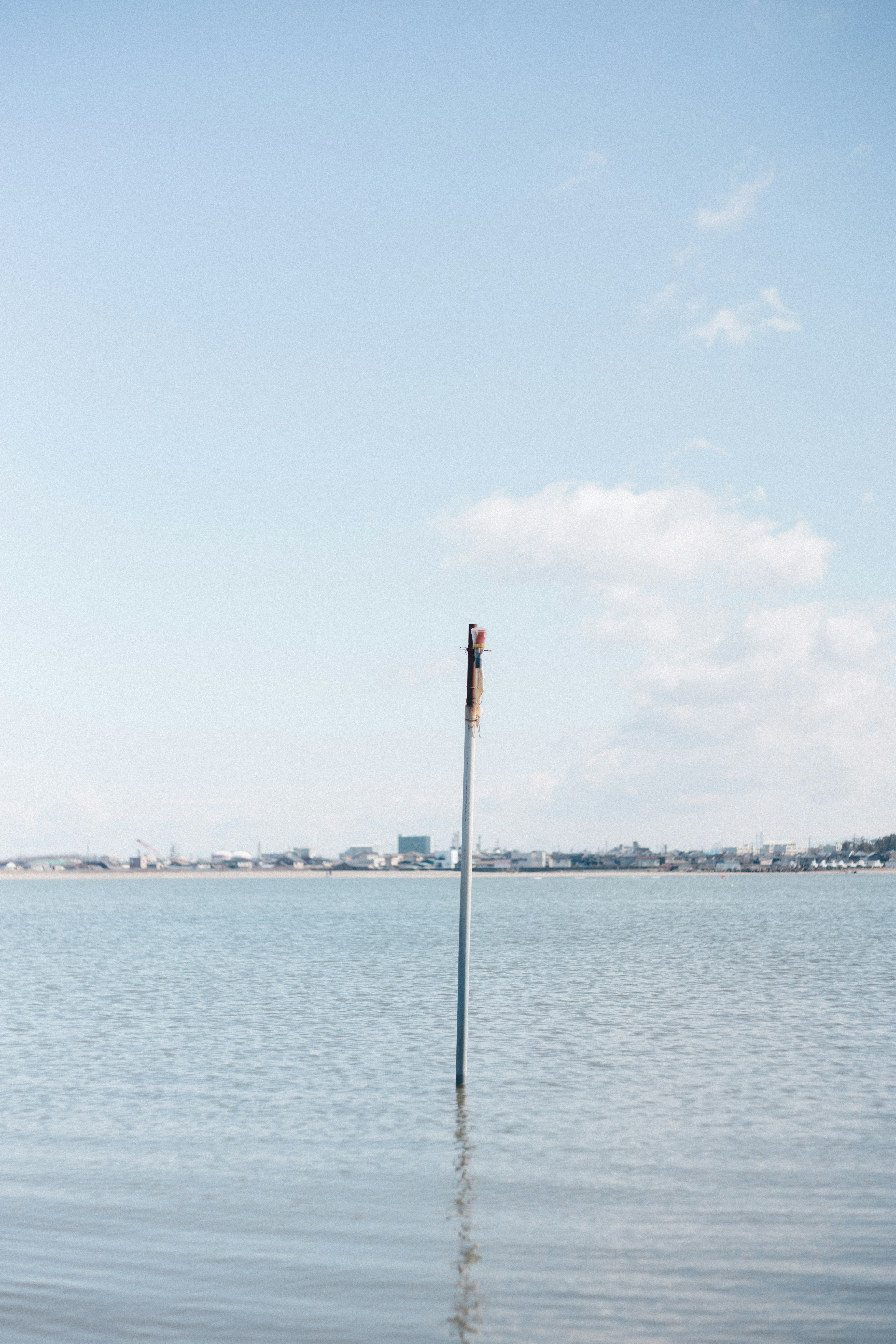 Poteau se tenant dans l'eau calme sous un ciel bleu