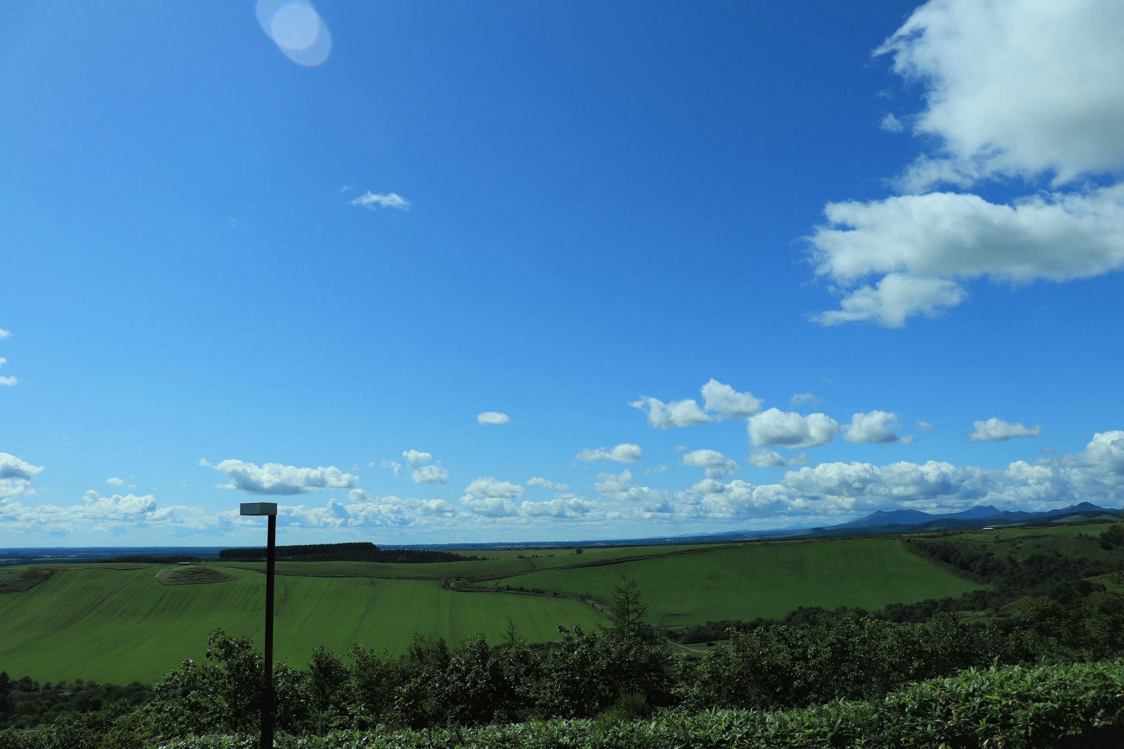 青い空と白い雲の下の緑の丘の風景