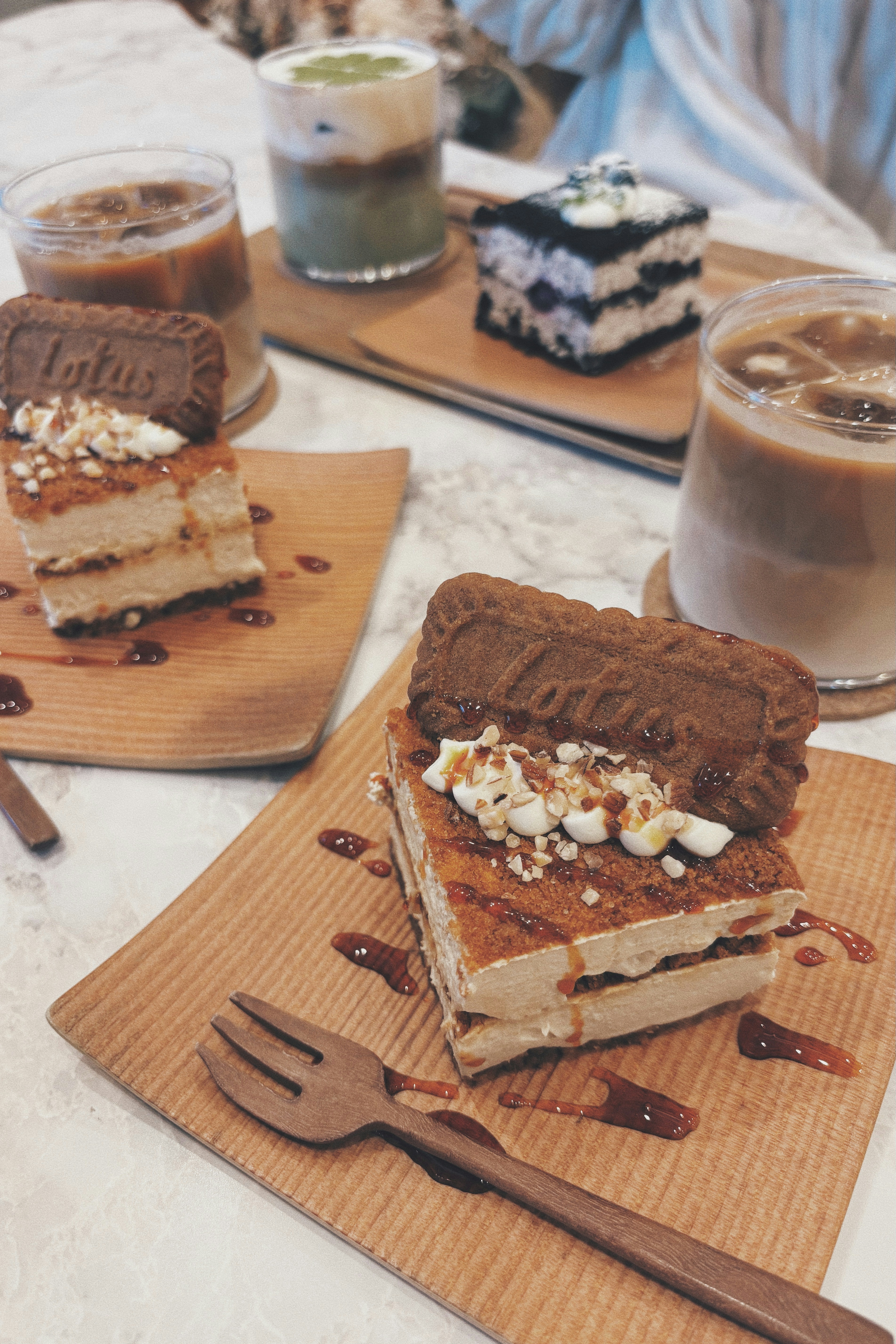 Kue gaya tiramisù dengan minuman cokelat dan kopi di atas piring kayu