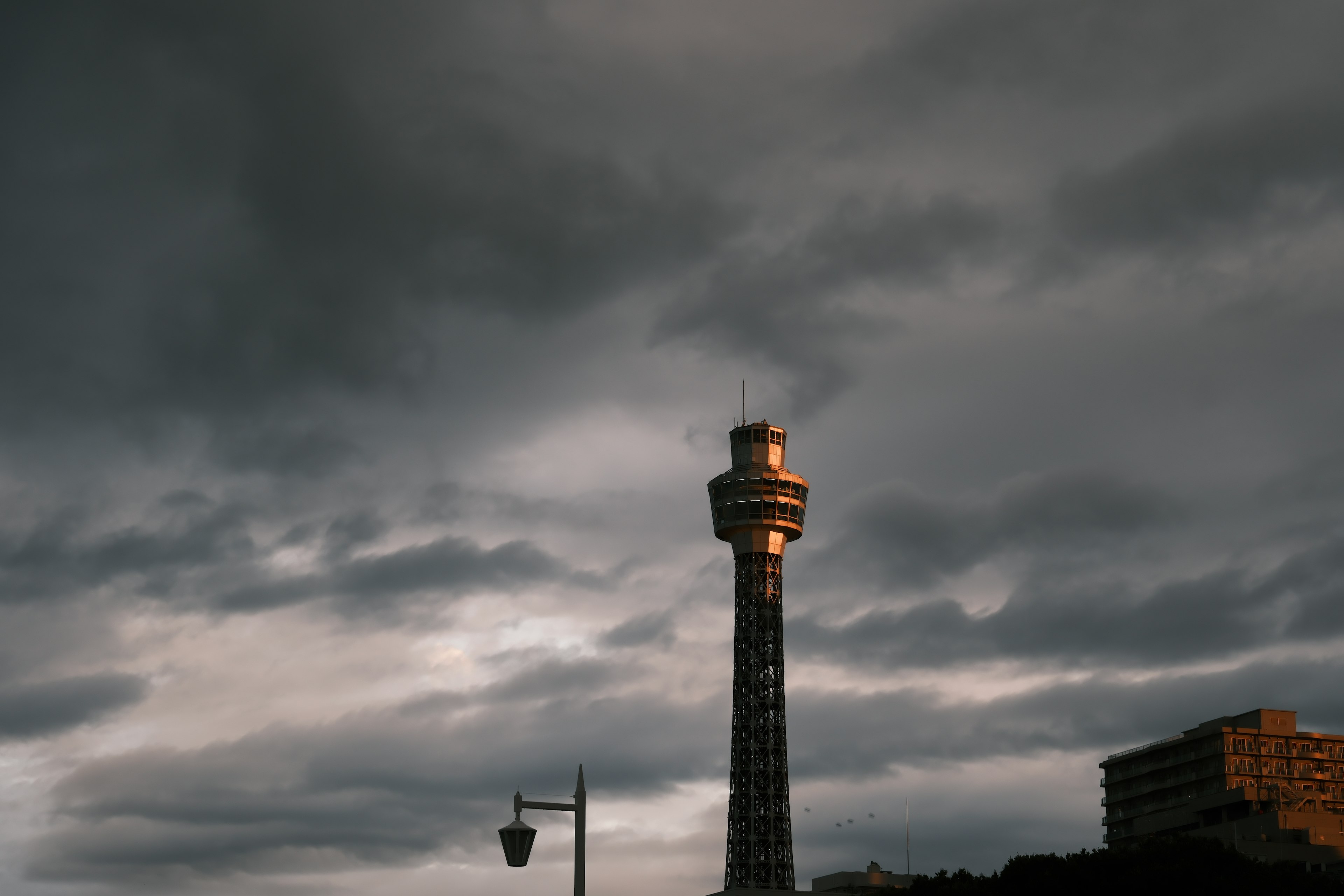 Silhouette of a tall tower under a dark, cloudy sky