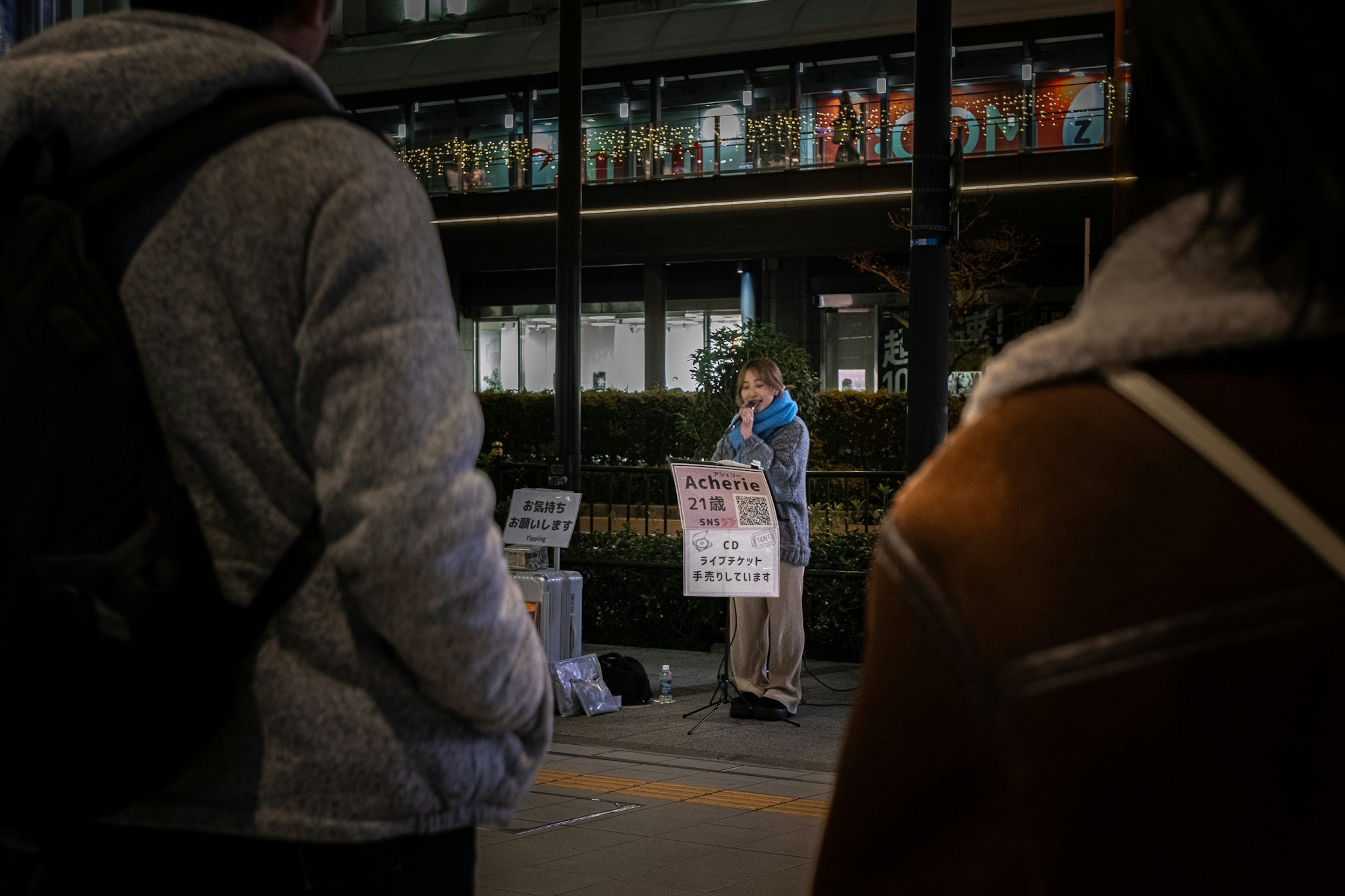 Une personne faisant un discours la nuit avec des spectateurs au premier plan