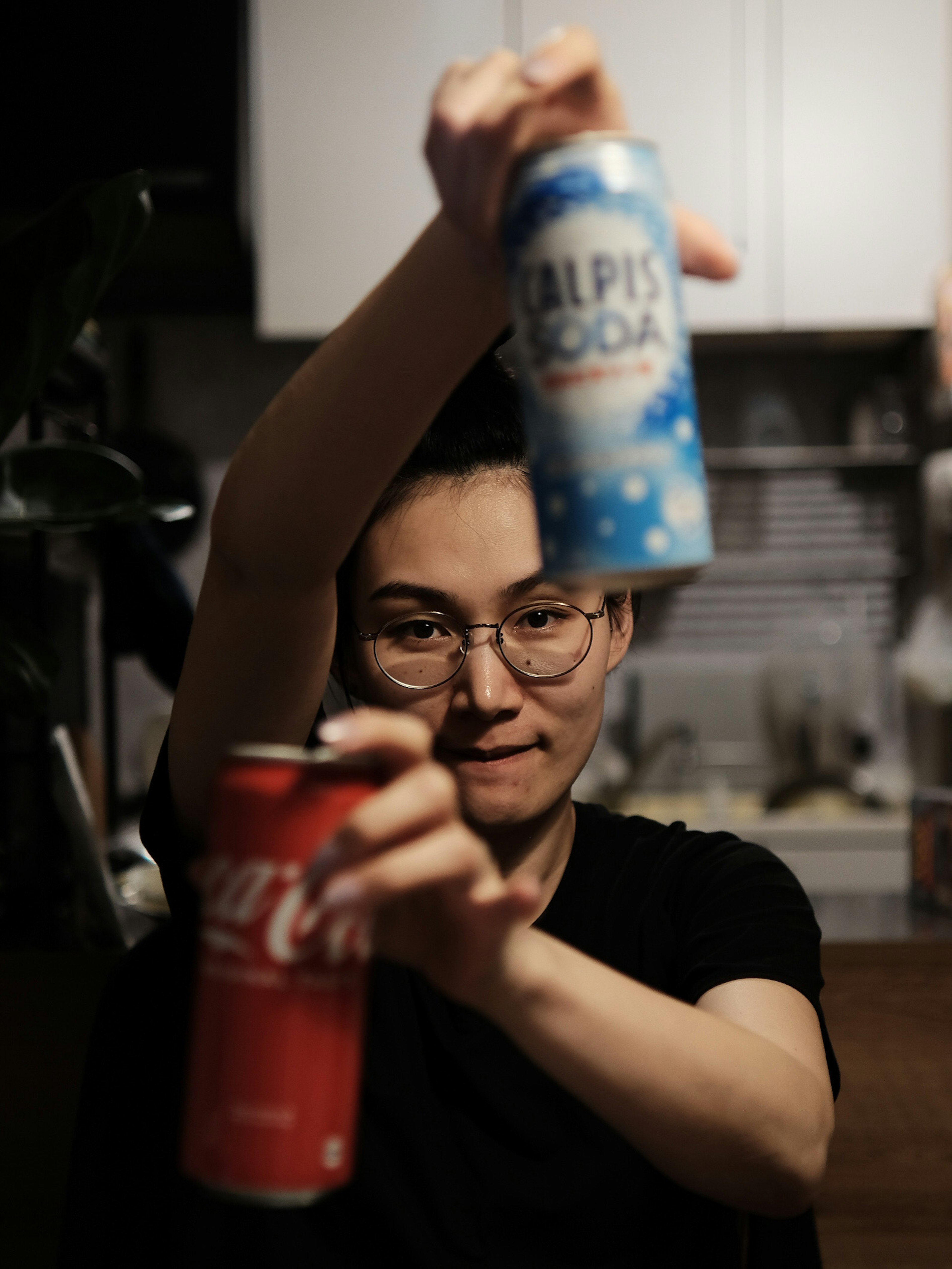 Person holding Coca-Cola and Alpis soda cans