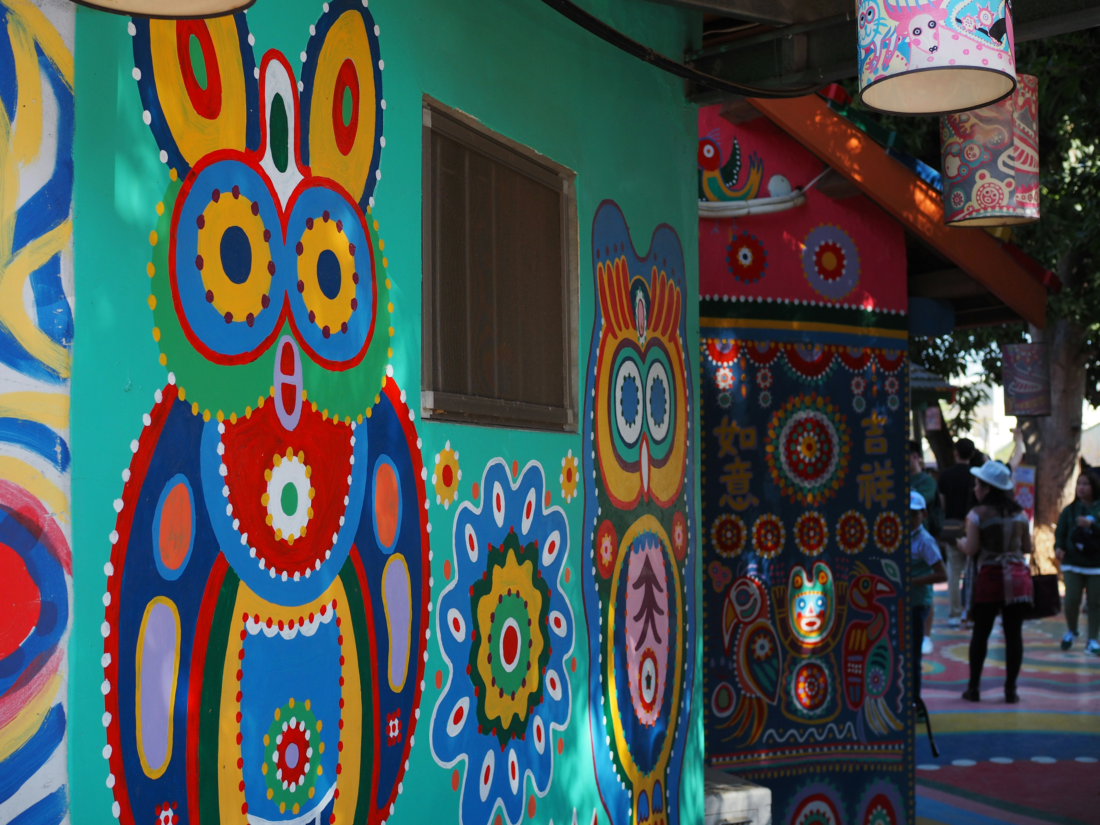 Colorful murals featuring owl and flower motifs on the side of a building