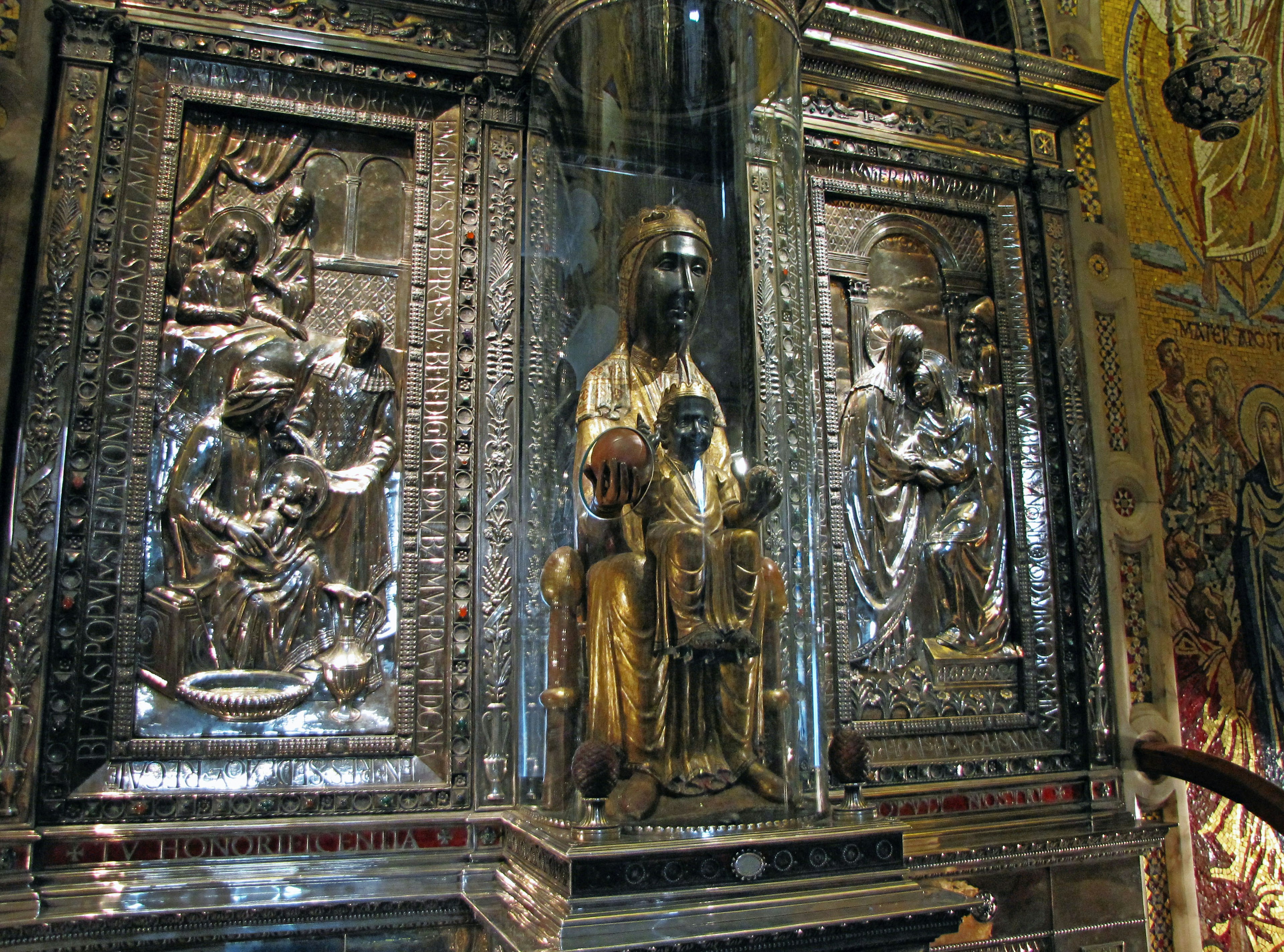 Intricate silver altar featuring a golden Madonna and child surrounded by detailed sculptures