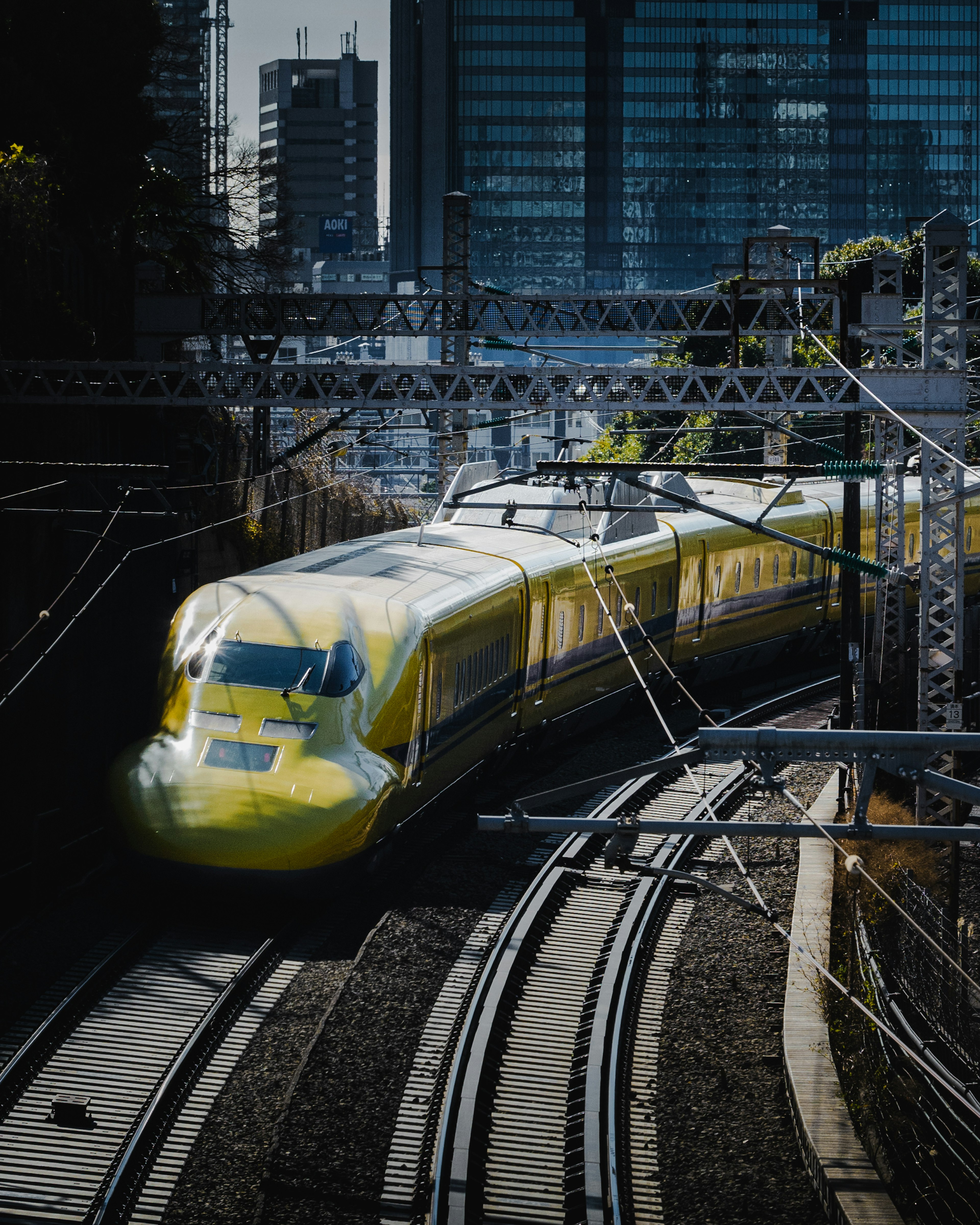 Yellow Shinkansen train navigating through urban tracks