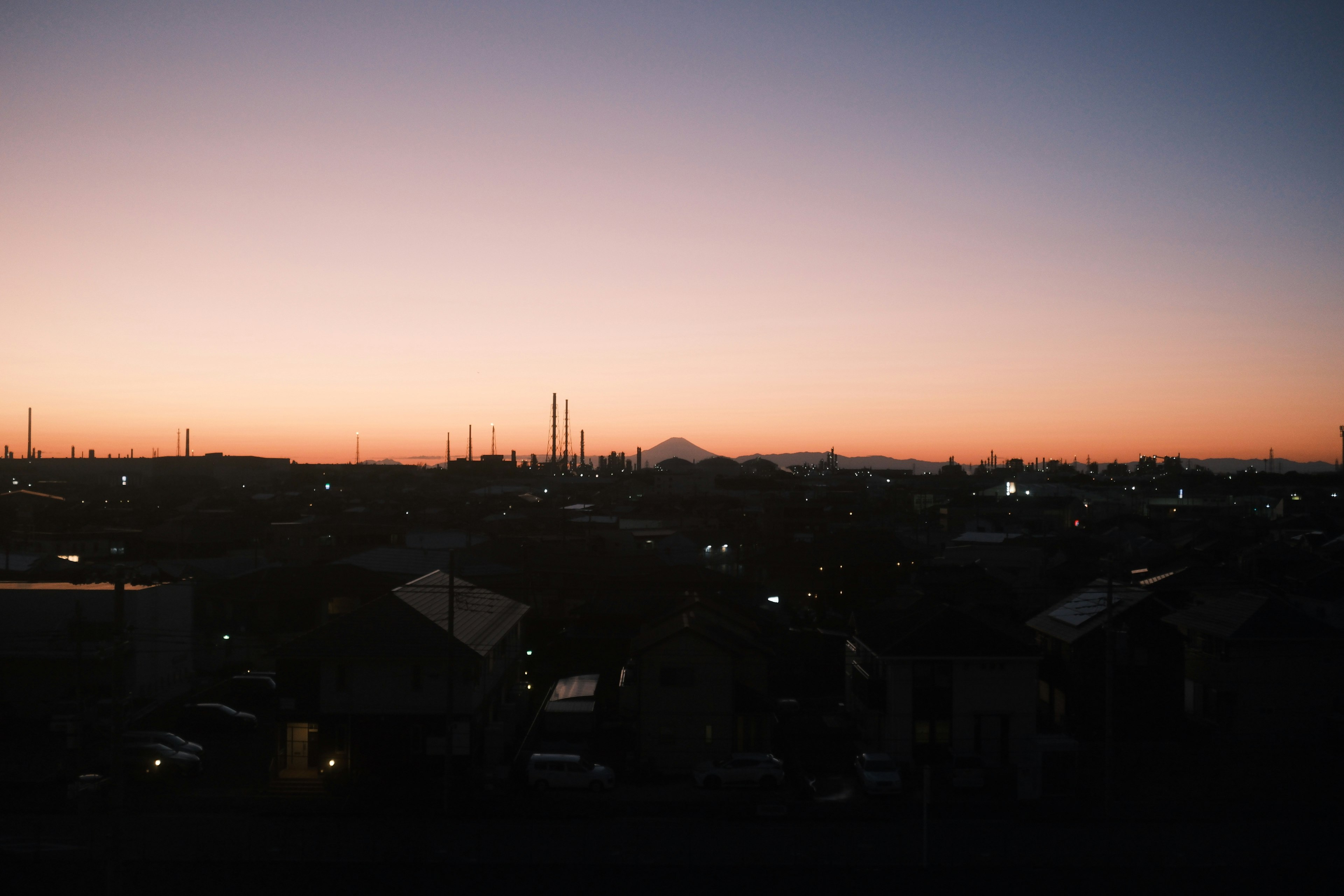 夕焼けの下に広がる都市のシルエットと富士山の遠景