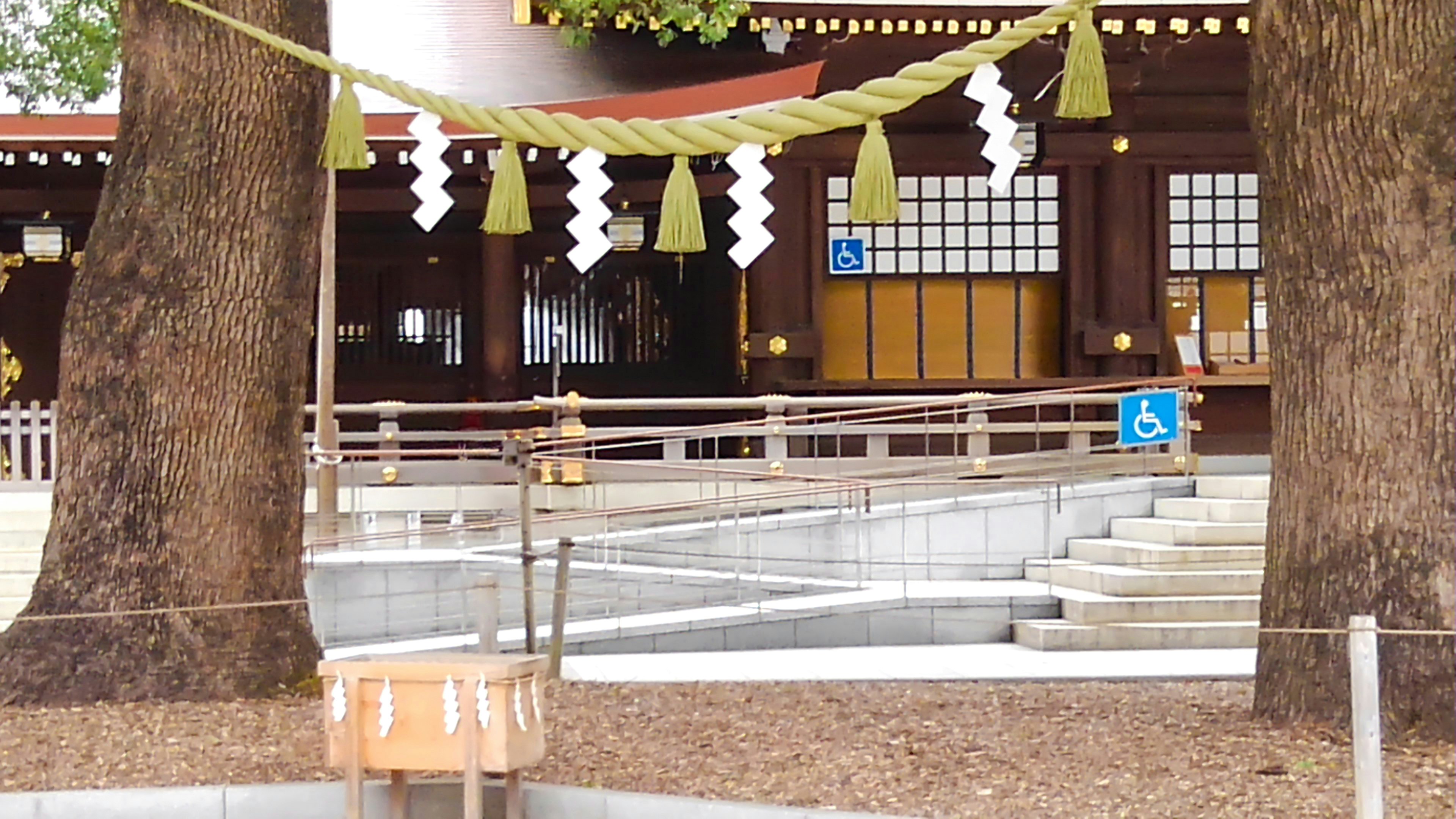 A view of a shrine courtyard featuring large trees and decorative elements