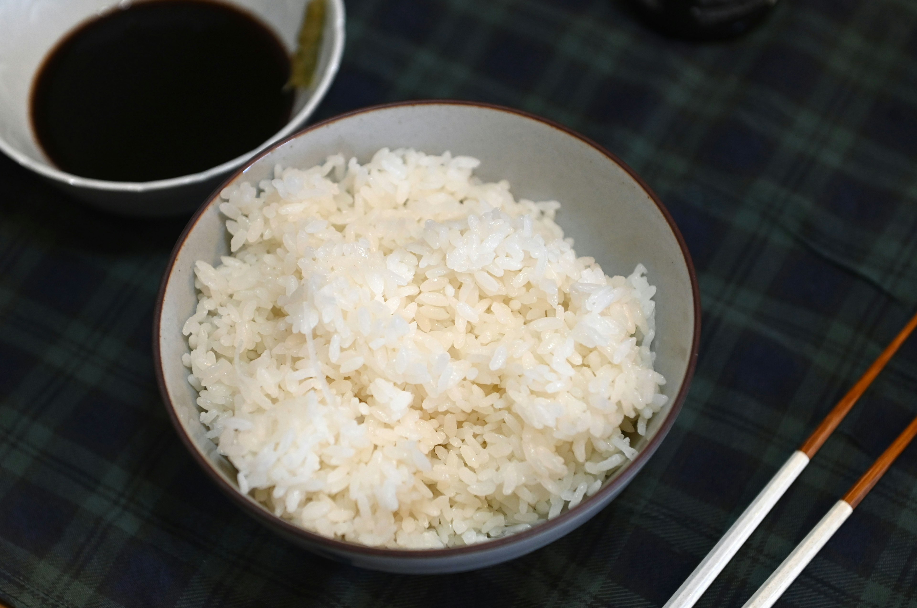 Mangkuk nasi putih lembut dengan piring kecil kecap di atas meja