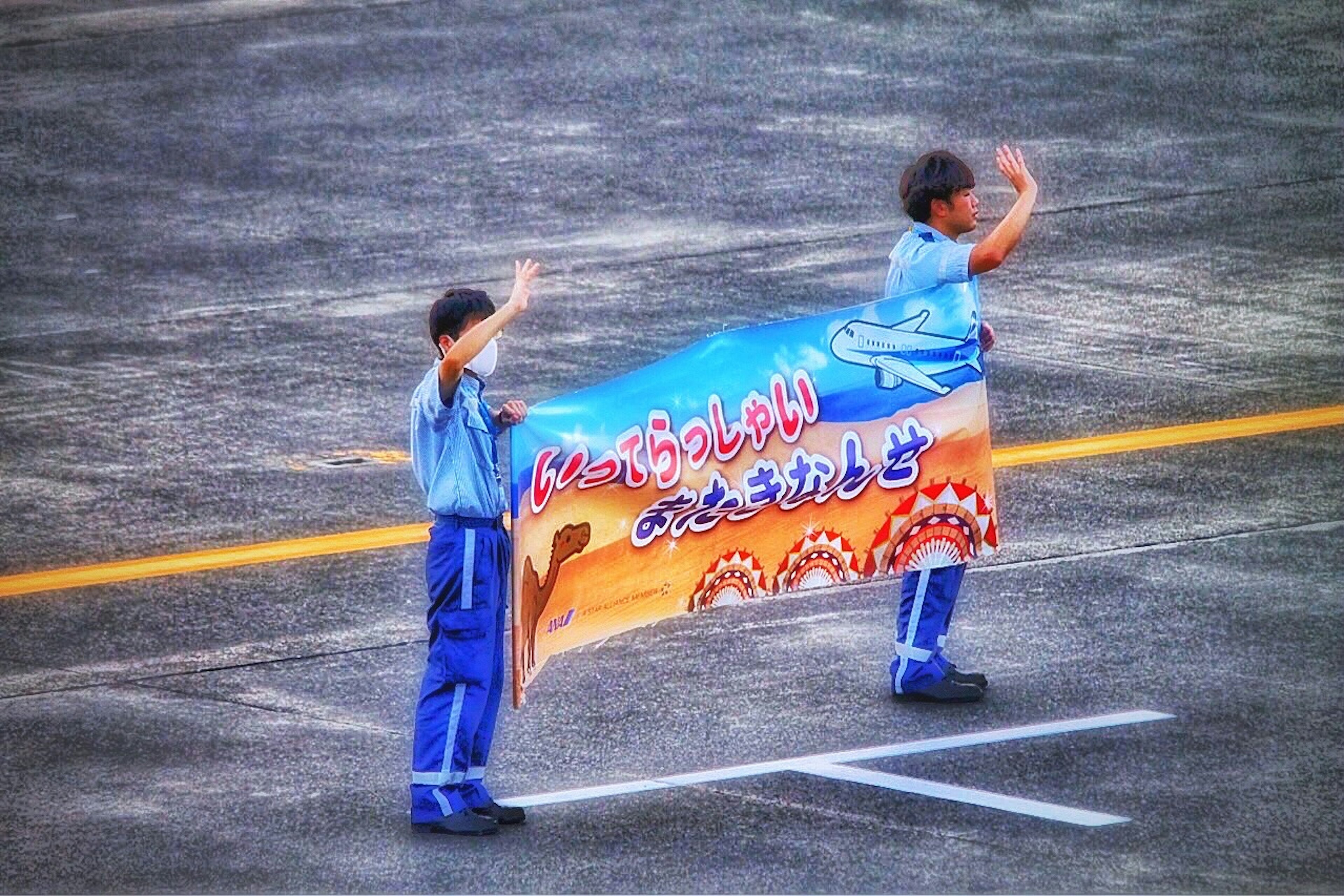 Dos personas en uniformes azules sosteniendo una gran pancarta