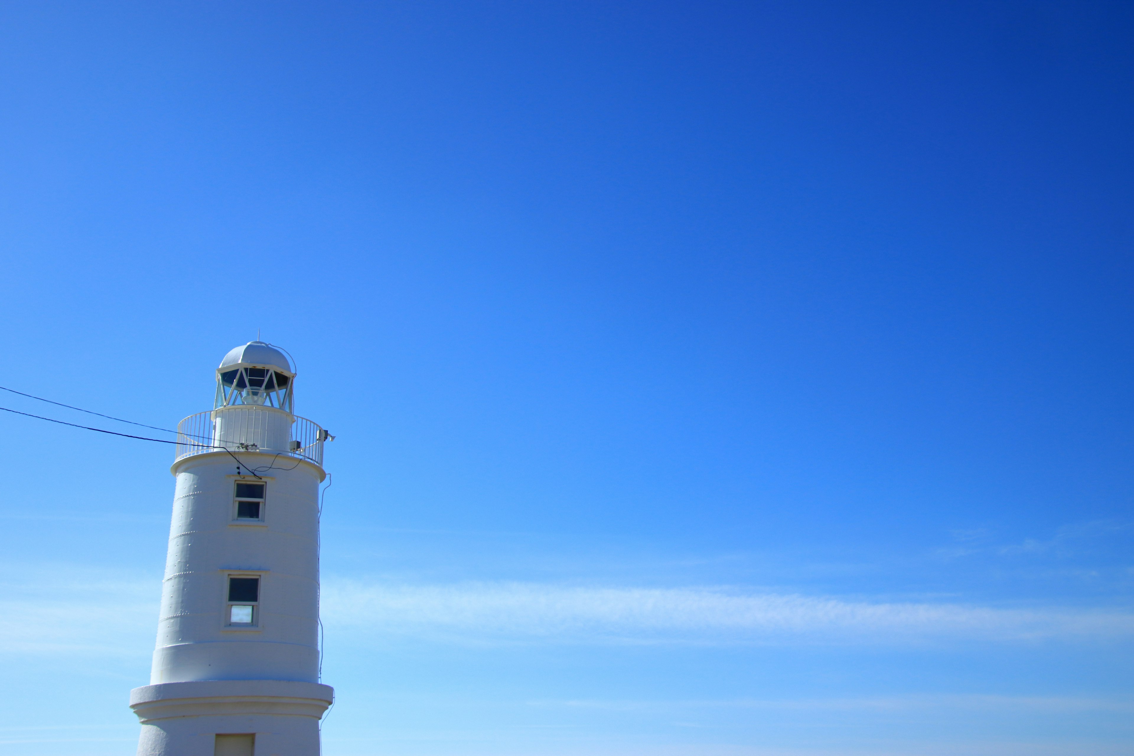 Imagen de un faro blanco bajo un cielo azul