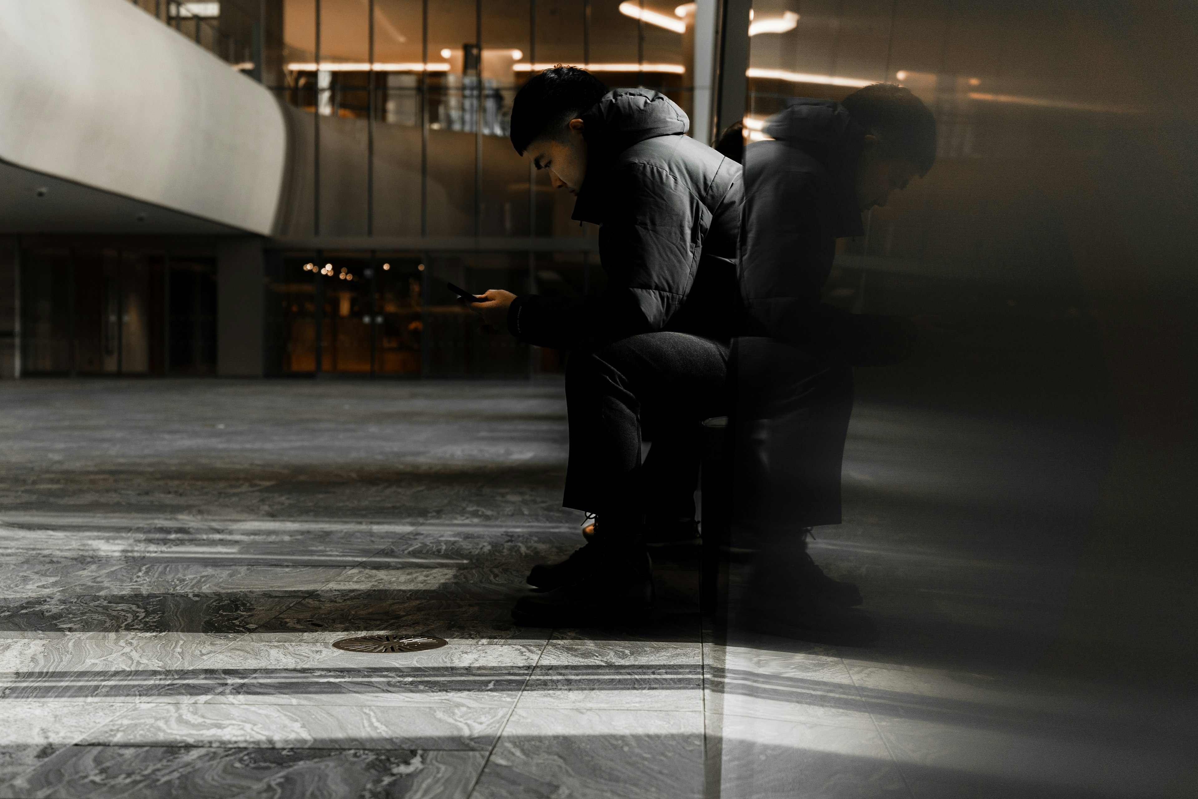 Silhouette of a person sitting indoors with a reflective surface