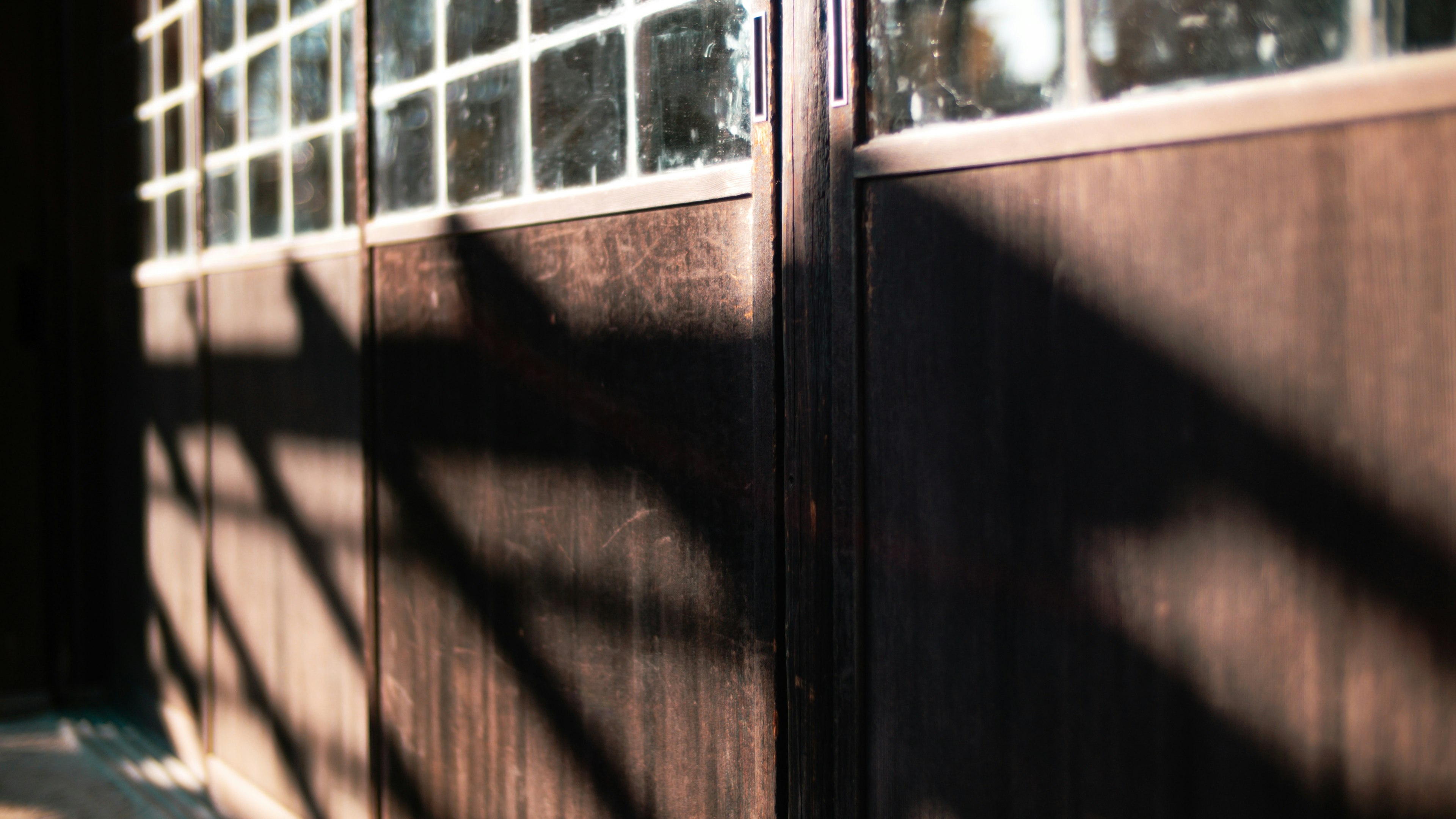 Puerta de madera con gran ventana que proyecta contrastes de luz y sombra