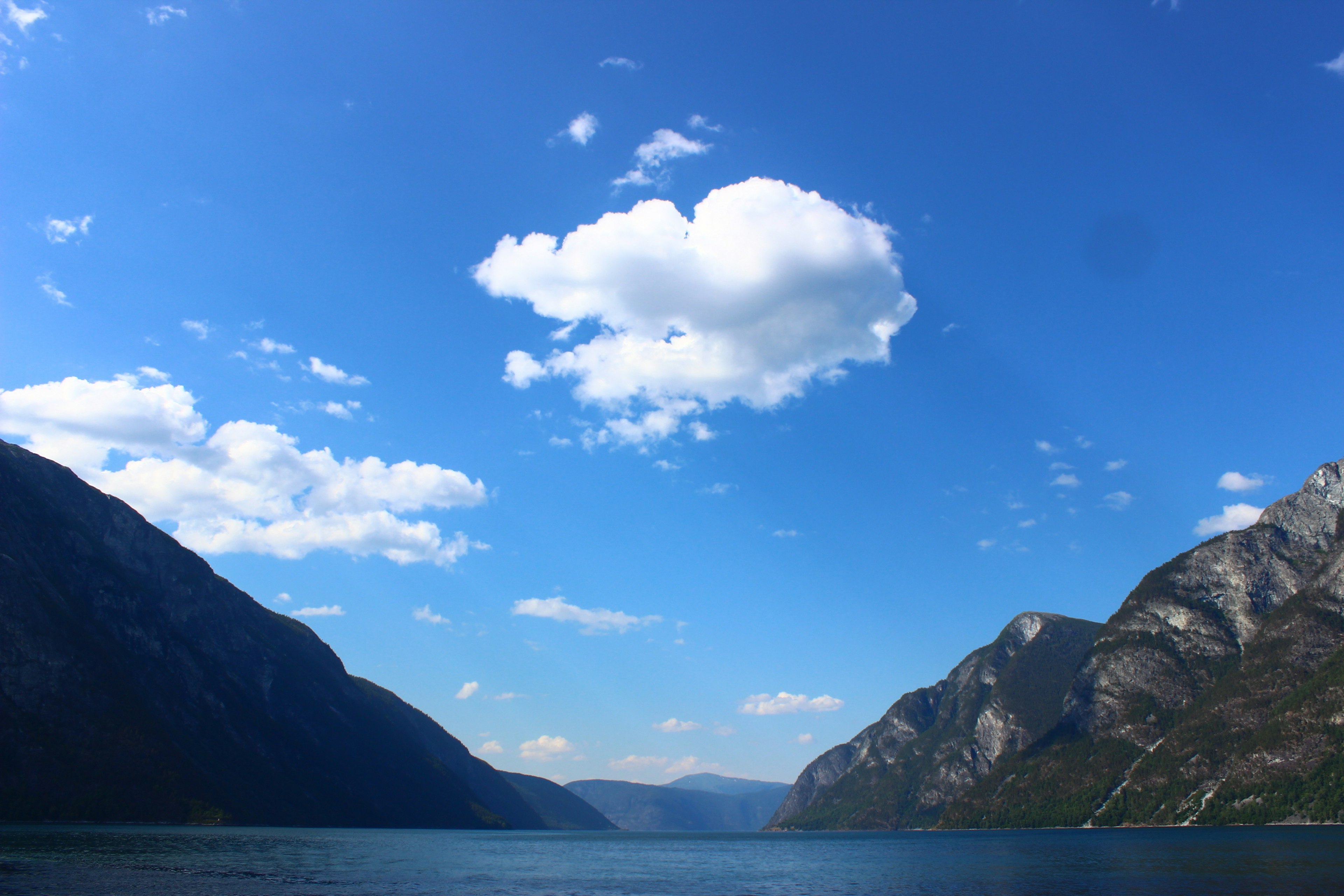 青空と雲、山々に囲まれた静かな湖の風景