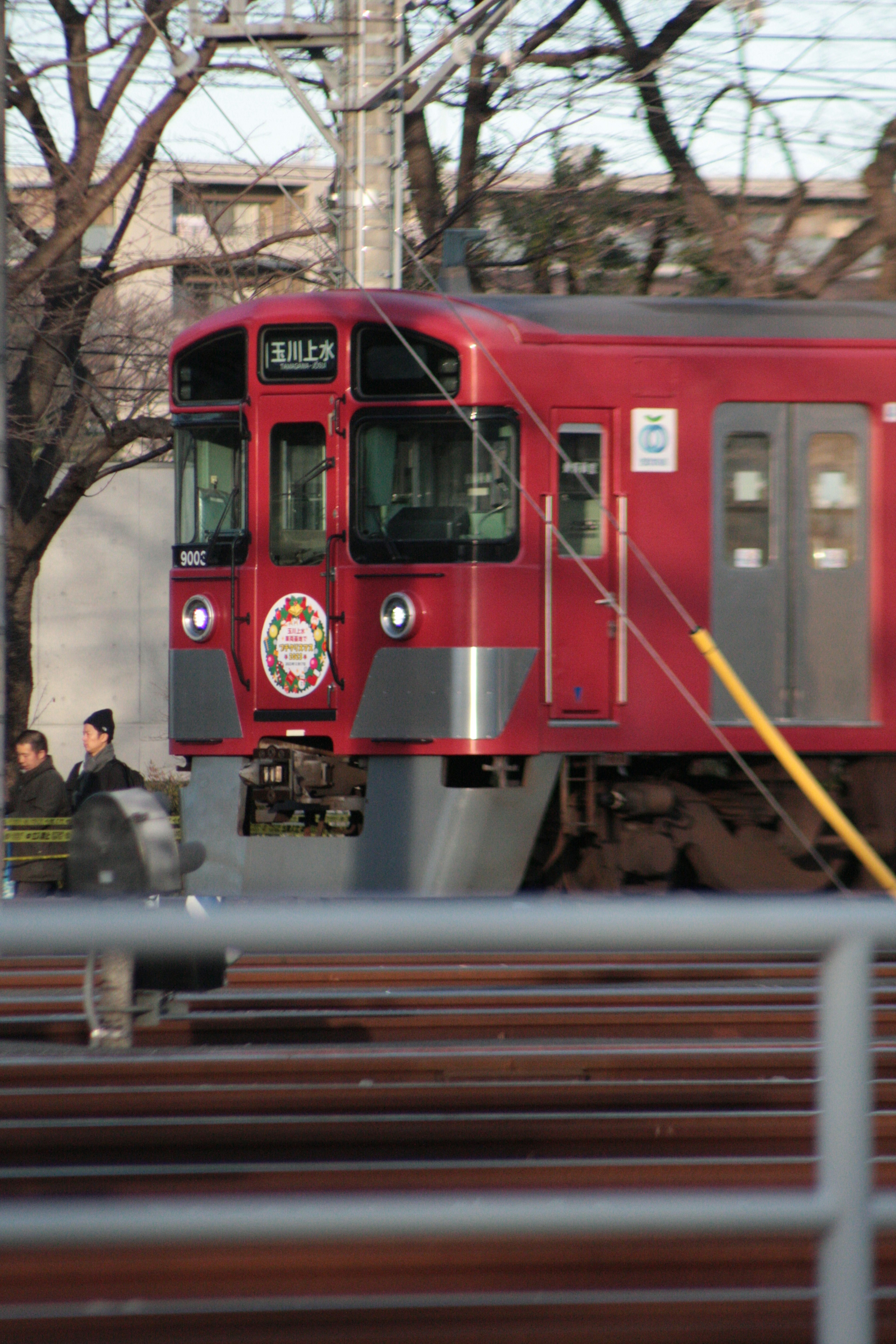 赤い電車が駅に停まっている様子と乗客