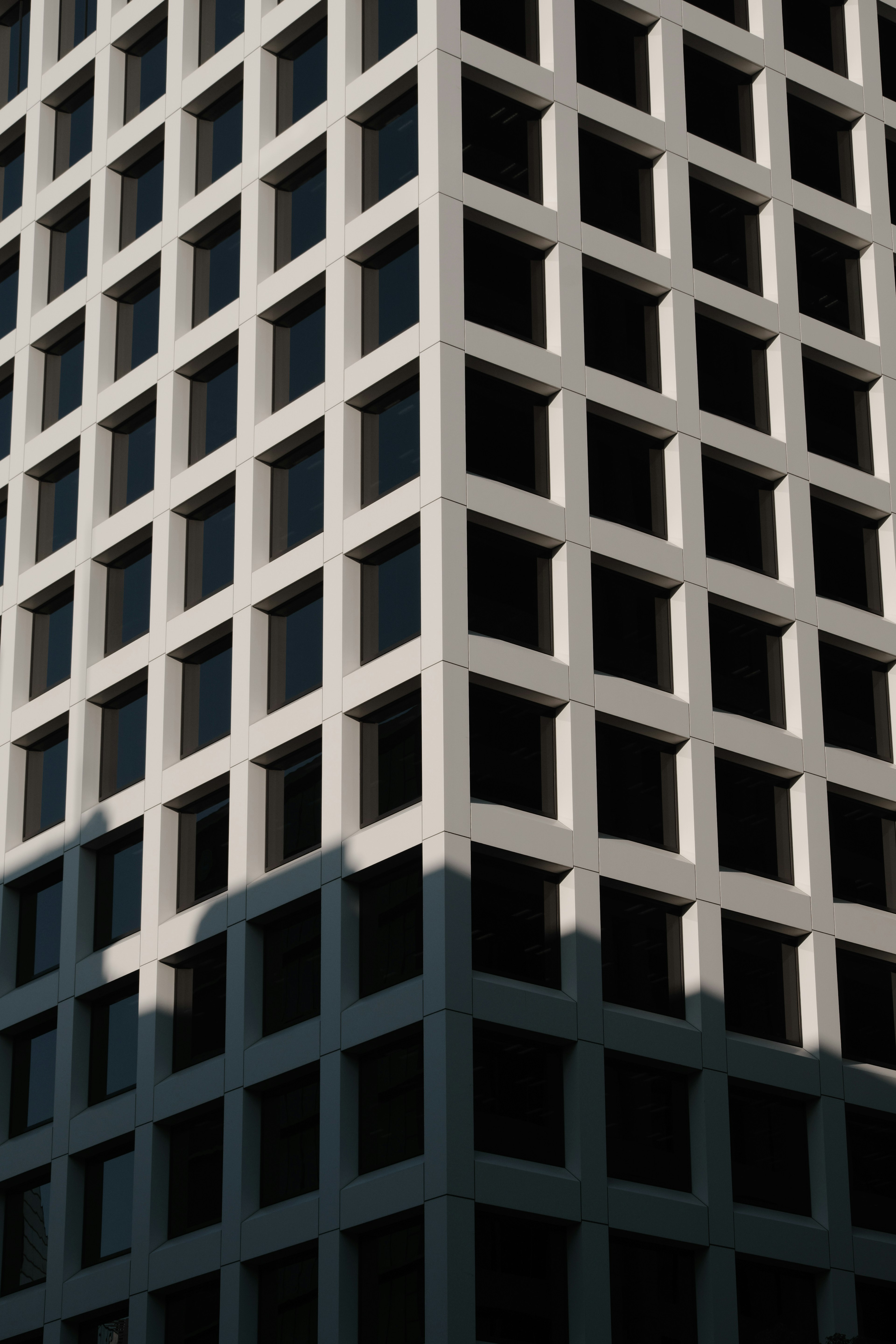 Close-up of a modern building corner with white facade and black windows