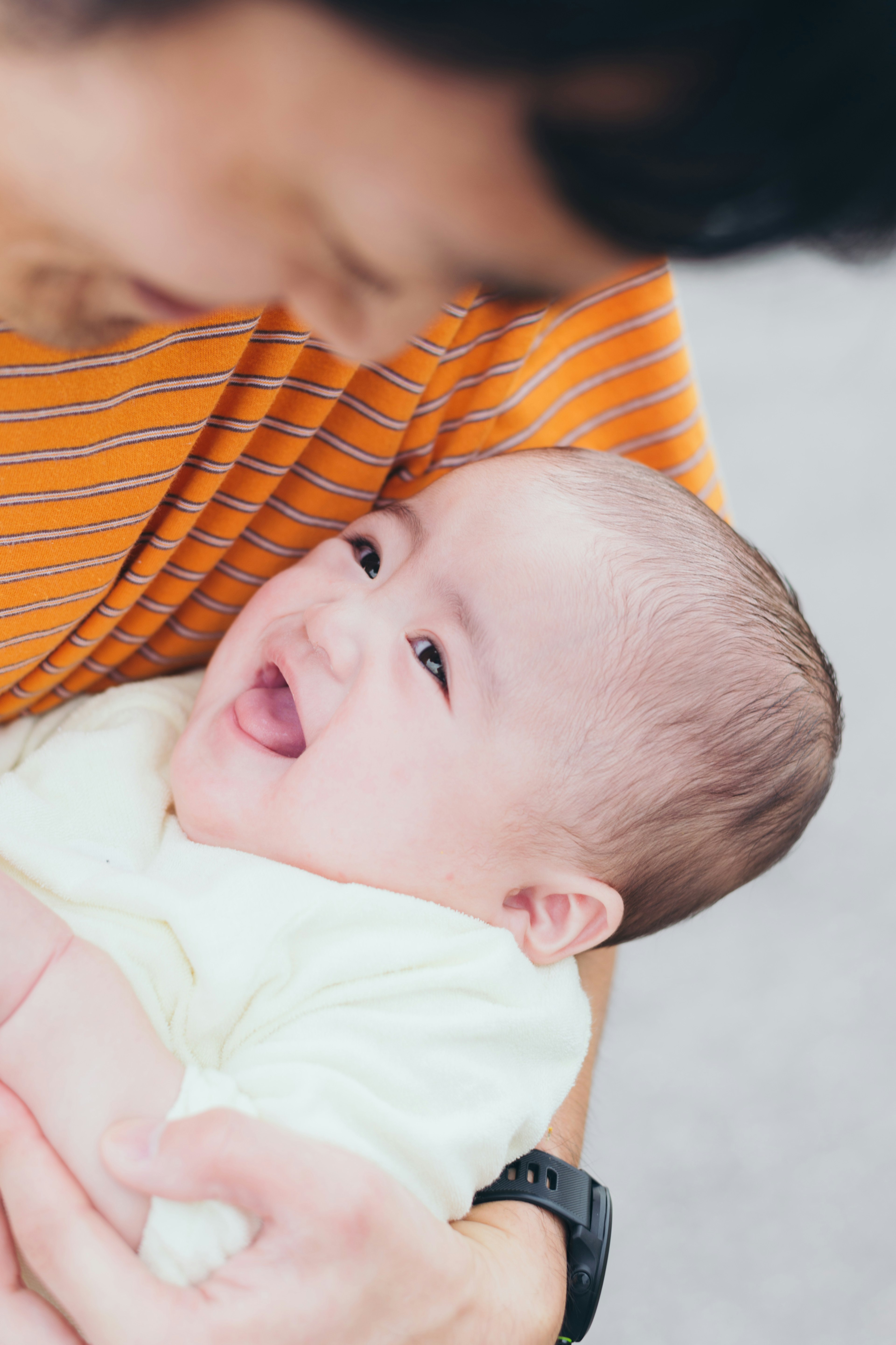 父親抱著微笑的嬰兒，面露快樂表情